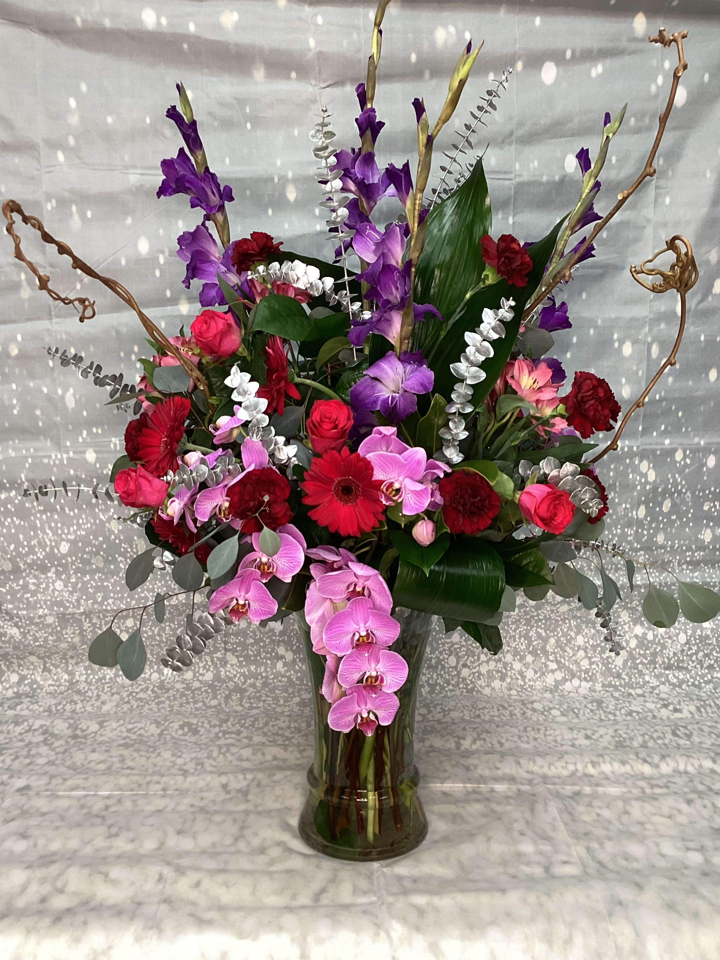 The 'Wow!' The 'Wow!' - This Exquisite, Rather Large Arrangement Will Knock You Off Your Feet. The Variety! The Moods! The Orchids! This Lush One-of-a-Kind Design Will Wow! Anyone. Artfully Arranged with Premium Mixed Flowers, Which Includes a Dozen Roses, Gladiolas, Intriguing Greenery Manipulation, Twisted Branches & Of Course Phalaenopsis Orchids. Your Custom Design Will Be Made with The Freshest Seasonally Available Flowers.