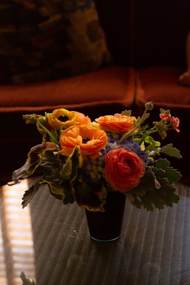Honey - A small arrangement of warmer toned seasonal flowers and soft texture, such as geraniums, in a cup. 