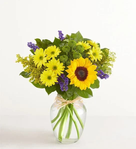 Fields of  Summer - Inspired by the colorful charm of the  countryside, our best-selling summer bouquet is gathered with fresh-picked blooms, revealing the rustic beauty of nature. Shades of golden yellow and rich blue pop against lush greenery, creating a timeless gift for someone special to enjoy.