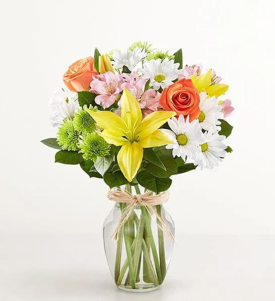 Fields of sun  - The rustic beauty of hand tied bouquets fresh. Handcrafted by our skilled artisan florists, this vibrant mix is gathered inside a clear glass vase tied with raffia for a touch of Old World charm.