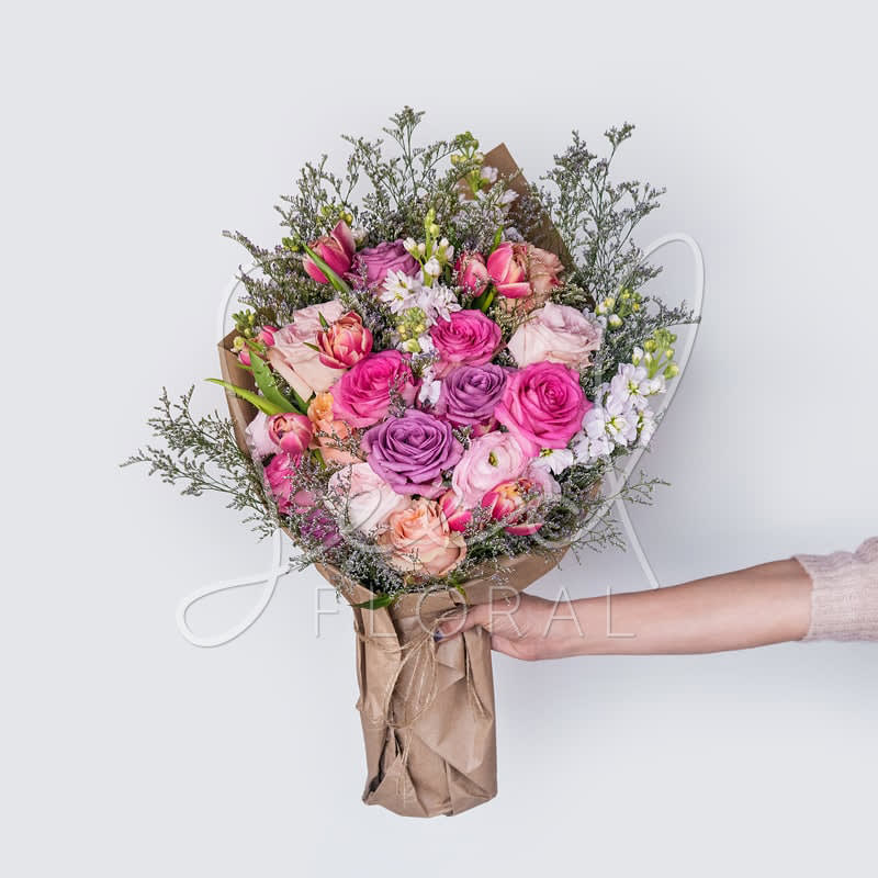 Lush Bouquet - A gorgeous wrapped bouquet designed with lush premium roses, stock, tulips, and ranunculus in pink berry tones.  **UPGRADE OPTIONS** STANDARD - Lush Bouquet  DELUXE - Lush Bouquet + Moonstruck Chocolate Bar PREMIUM - Lush Bouquet + Moonstruck Chocolate Bar + Soy Candle (assorted scents)