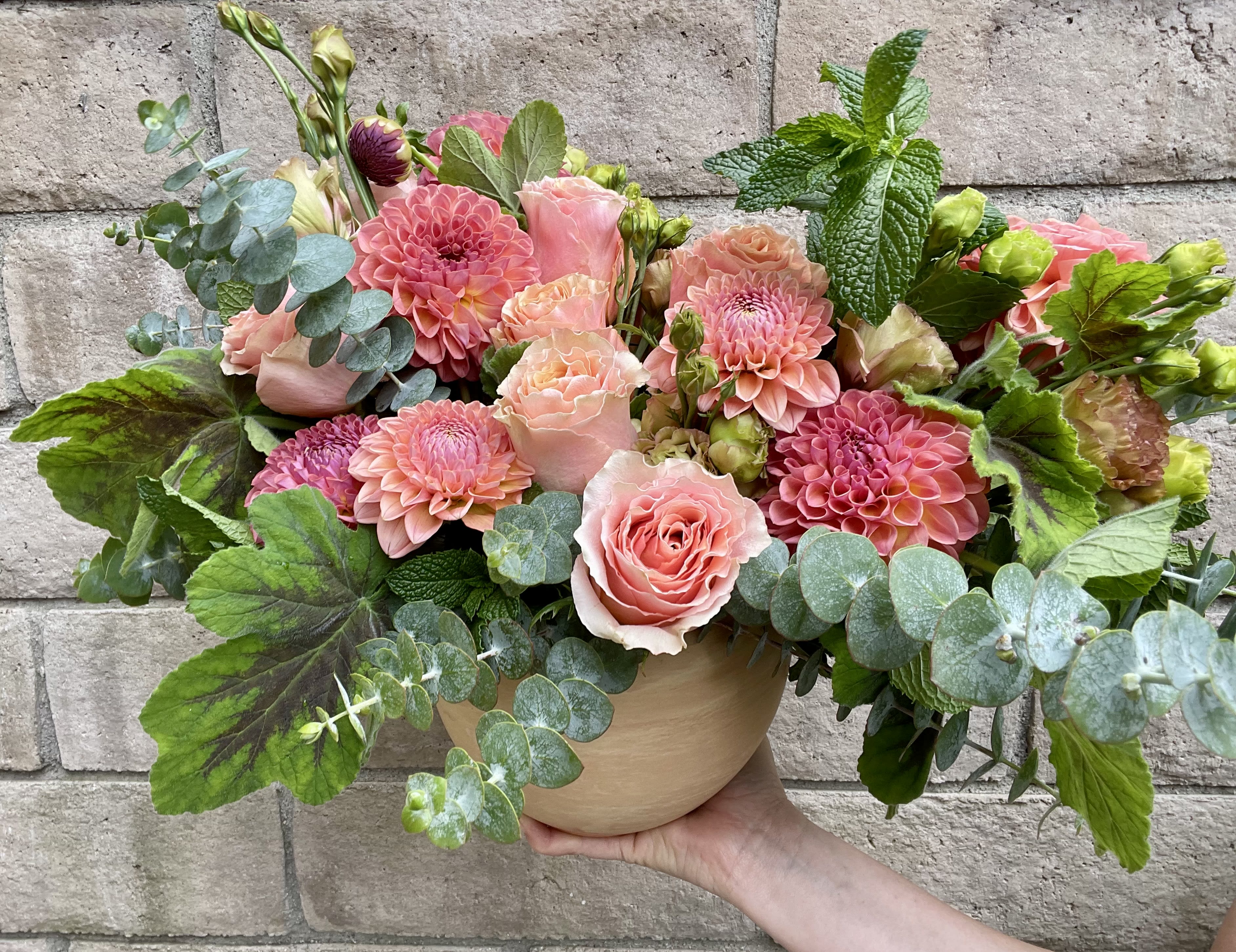 She's A Peach - A divine monochromatic arrangement of peach and light coral toned Dahlias and Roses accented with fragrant Eucalyptus, Geranium and Mint (seasonally available) in a beautiful and chic terracotta vase. For a lover of color an texture, this gift is a dreamy.