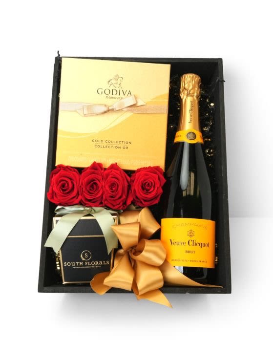 Veuve Clicquot Classic Champagne Gift Box Veuve Clicquot Classic Champagne Gift Box - GBVCC - Veuve Clicquot Classic Champagne Gift Box The Veuve Clicquot Classic Champagne Gift Box (yellow label) is the top seller from our Collection. This box includes the very popular Classic Clicquot Champagne, 8pc Godiva Chocolate, Scented Candle Wrapped in Satin Ribbons, Preserved Red Roses on a bed of Black & Gold shredded glitz. The Preserved Roses are frozen in time and will remain as a beautiful keepsake. Also Available in Preserved Pink Roses.