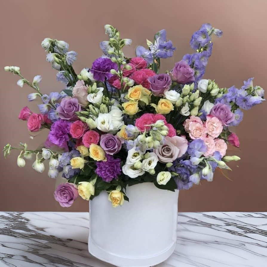 Los Angeles Charm in Every Petal - Celebrate life’s special moments with this radiant flower box, featuring an exquisite blend of roses, lisianthus, delphinium, and carnations. Each bloom is carefully selected to create a visually stunning arrangement that radiates elegance and charm.  Perfect for gifting or as décor, this floral creation is ideal for wedding venues, office buildings, and private events. Whether you're sending a heartfelt gesture to loved ones or enhancing the ambiance at local landmarks such as Griffith Park, The Getty Center, or your favorite restaurant, this flower box exudes luxury and thoughtfulness.  At Lotus Event Decor, we provide exceptional flower delivery services in Los Angeles, catering to funeral homes, corporate offices, and event spaces. Our commitment to quality ensures that every arrangement arrives fresh and flawless, making it a perfect choice for any occasion.
