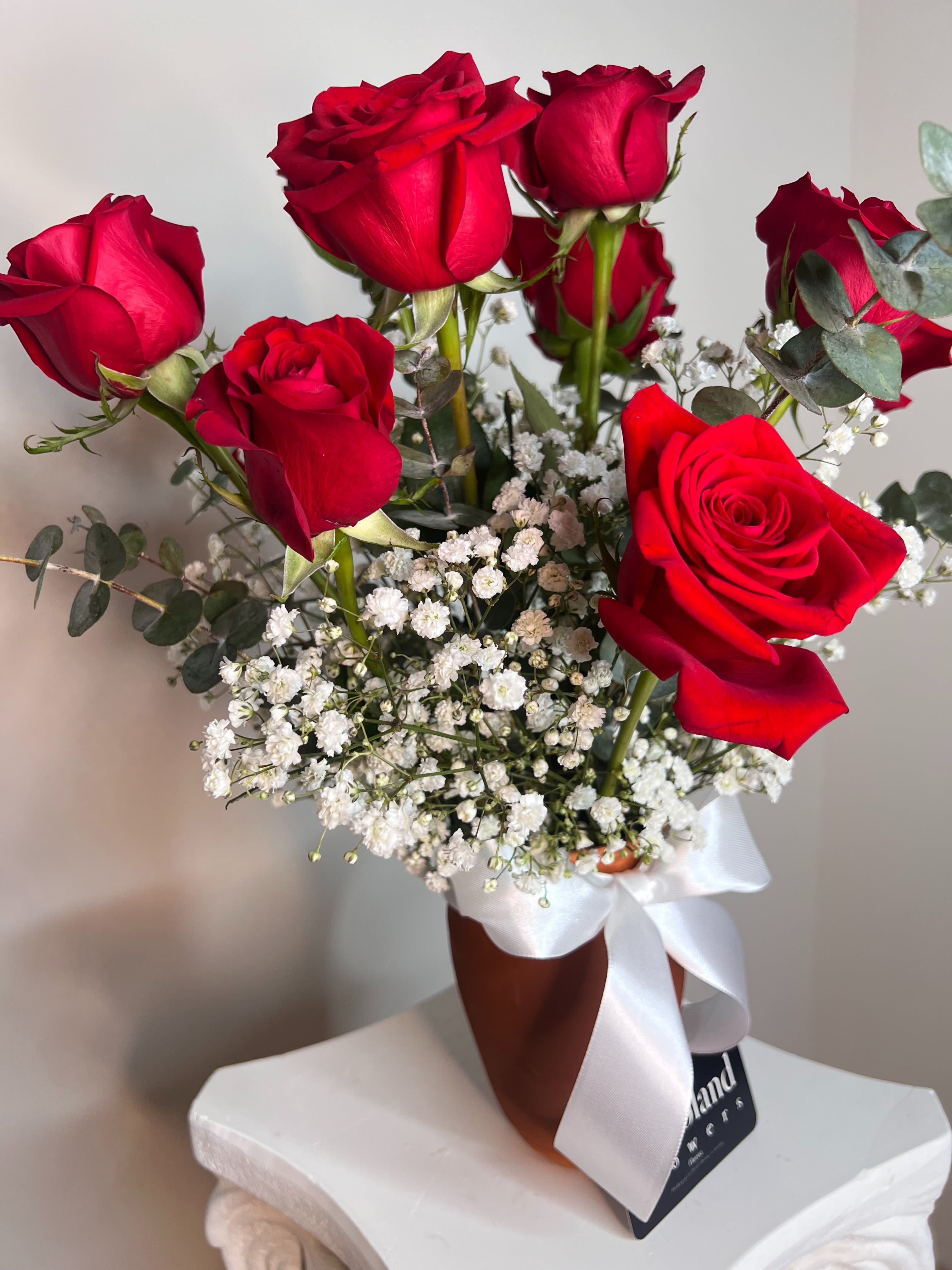 Jarrito in Bloom (May promotion) - Each clay jar is one of a kind, handcrafted with small imperfections that make it special—just like true love. This arrangement of red roses, baby’s breath, and eucalyptus not only expresses affection, it also celebrates what’s made with heart. A detail full of Mexican essence, created by Flevoland Flowers.