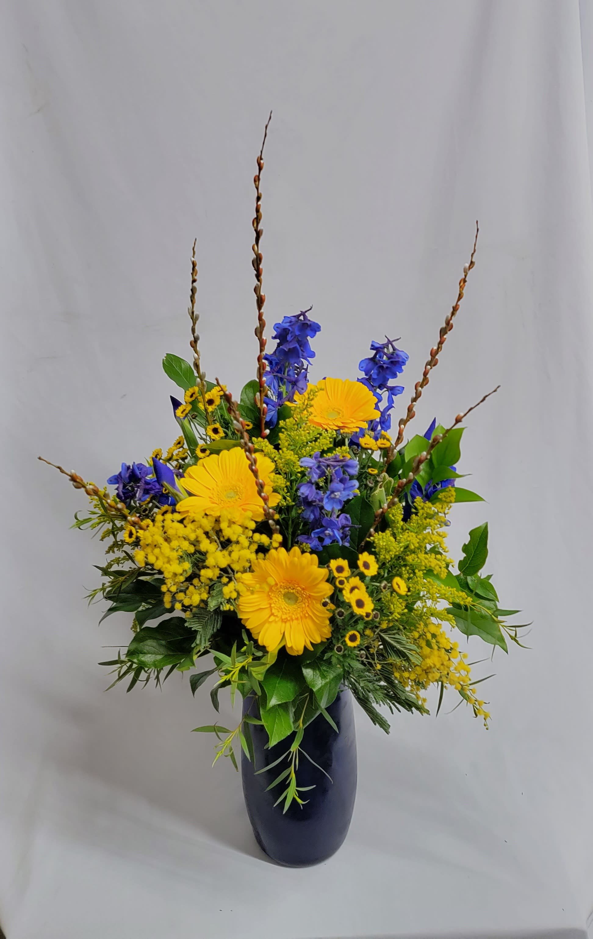 Blue & Gold Blue & Gold - Perfect for graduation or any summer celebration. Includes gerbera daisies, belladonna and chrysanthemums in a cobalt blue vase.