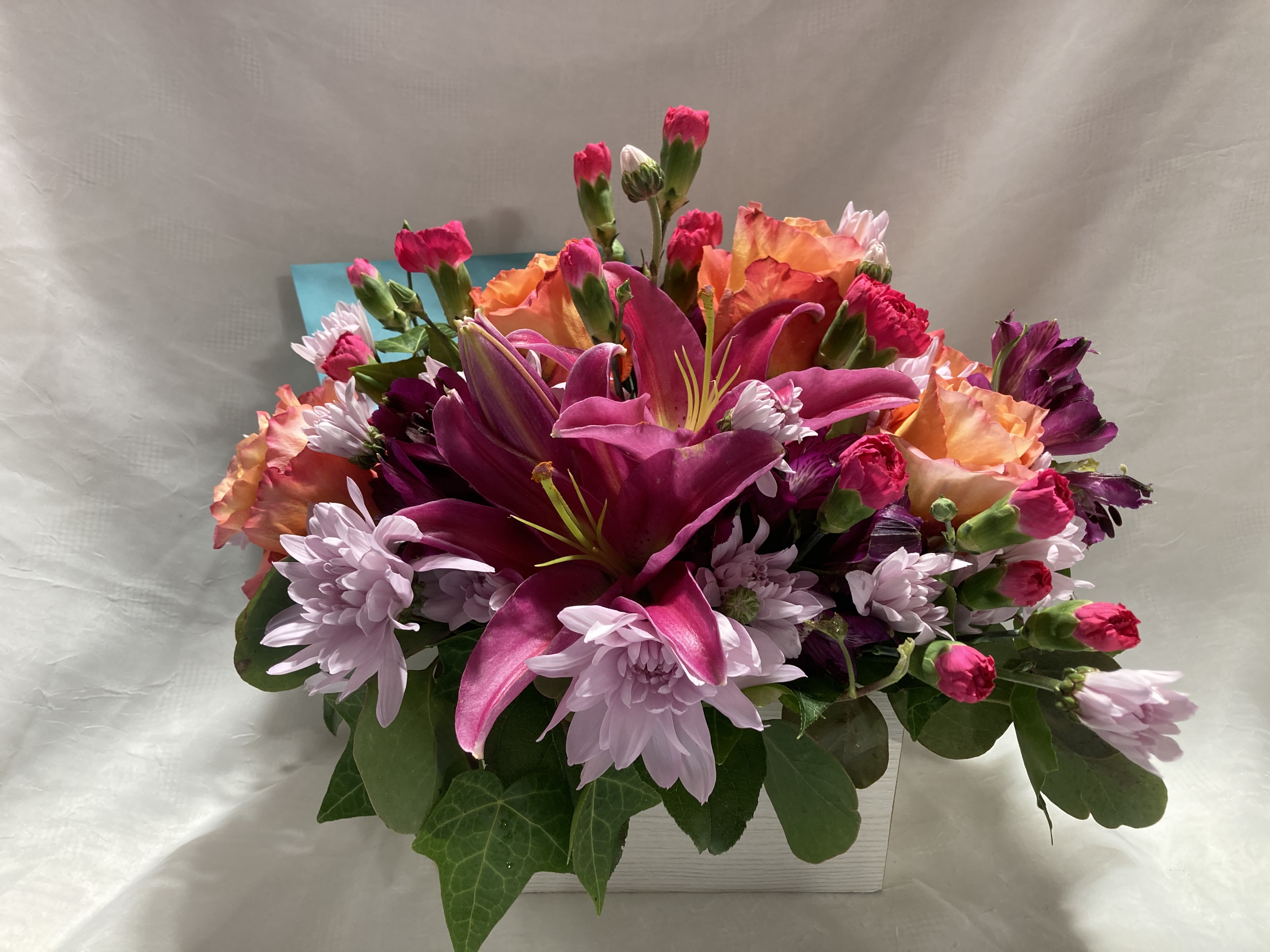 Hot pink and orange window box - These hot pink and orange blooms in a white window box arrangement are sure to please the most modern of recipients.  This bouquet includes roses, lilies, alstroemeria, mums, and miniature carnations, as available.  
