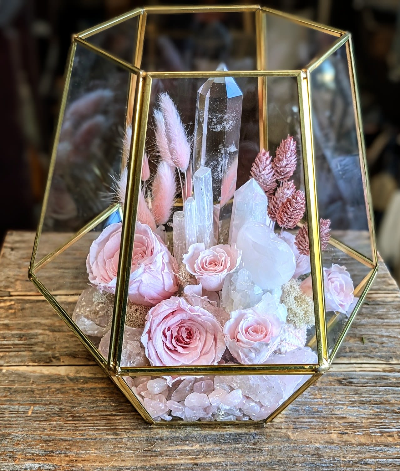 Giselle- Preserved Roses With Quartz And Rose Quartz Accents Giselle- Preserved Roses With Quartz And Rose Quartz Accents - Giselle Delicate, dreamy, and full of quiet magic, Giselle is a luxurious terrarium arrangement from Windmill Floral Expressions in Las Vegas, blending natural elegance with celestial charm. Housed in a faceted glass vessel framed with gold, this design feels like a keepsake from a fairytale—timeless, intentional, and full of light. Soft rose quartz crystals form the heart of the arrangement, radiating love and warmth beneath preserved blush roses and spray roses, their petals gently unfolding in romantic stillness. Wisps of pink bunny tails and amaranth add texture and movement, while clear quartz and selenite towers rise through the center like beams of serenity and light. Finished with natural moss and dried botanicals, Giselle makes a serene centerpiece, a heartfelt gift, or a decorative accent filled with grace and intention. Handcrafted with love in Las Vegas, NV. Same-day delivery available.