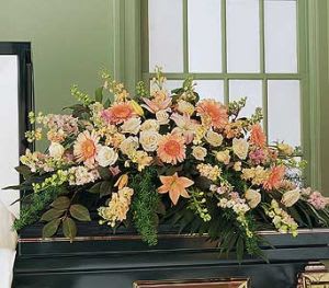 Peach Comfort Spray -CS16 Peach Comfort Spray -CS16 - Since peach is one of the most naturally comforting colors, this half-couch spray is sure to provide plenty of comfort to all those who care. A half-couch casket flower spray is delivered decorated with peach gerberas, larkspur, lilies, roses, stock and camellia, along with emerald palm and Spengeri. Approximately 47" W x 30" H