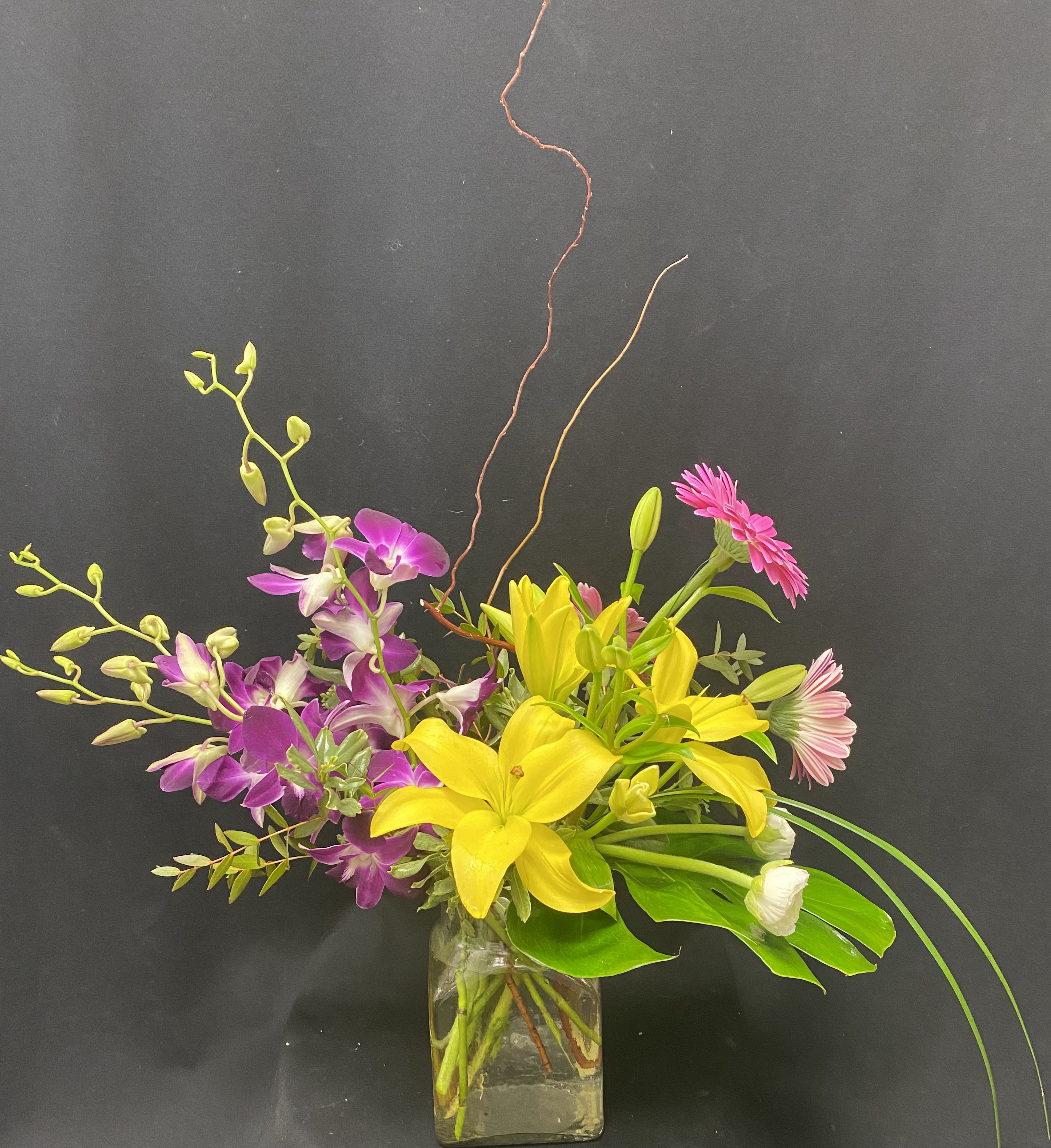 Brightening your day - Vase orchids, lilies, gerberas, ranaculus, curly willow, monstera and lilly grass. 