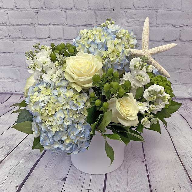 Ocean Breeze  - This Wonderful Bouquet features Blue and white flowers including Hydrangeas, Delphinium, Thistle and a star fish.     *Container and Flowers may differ slightly from what is shown in the picture depending on availability and season