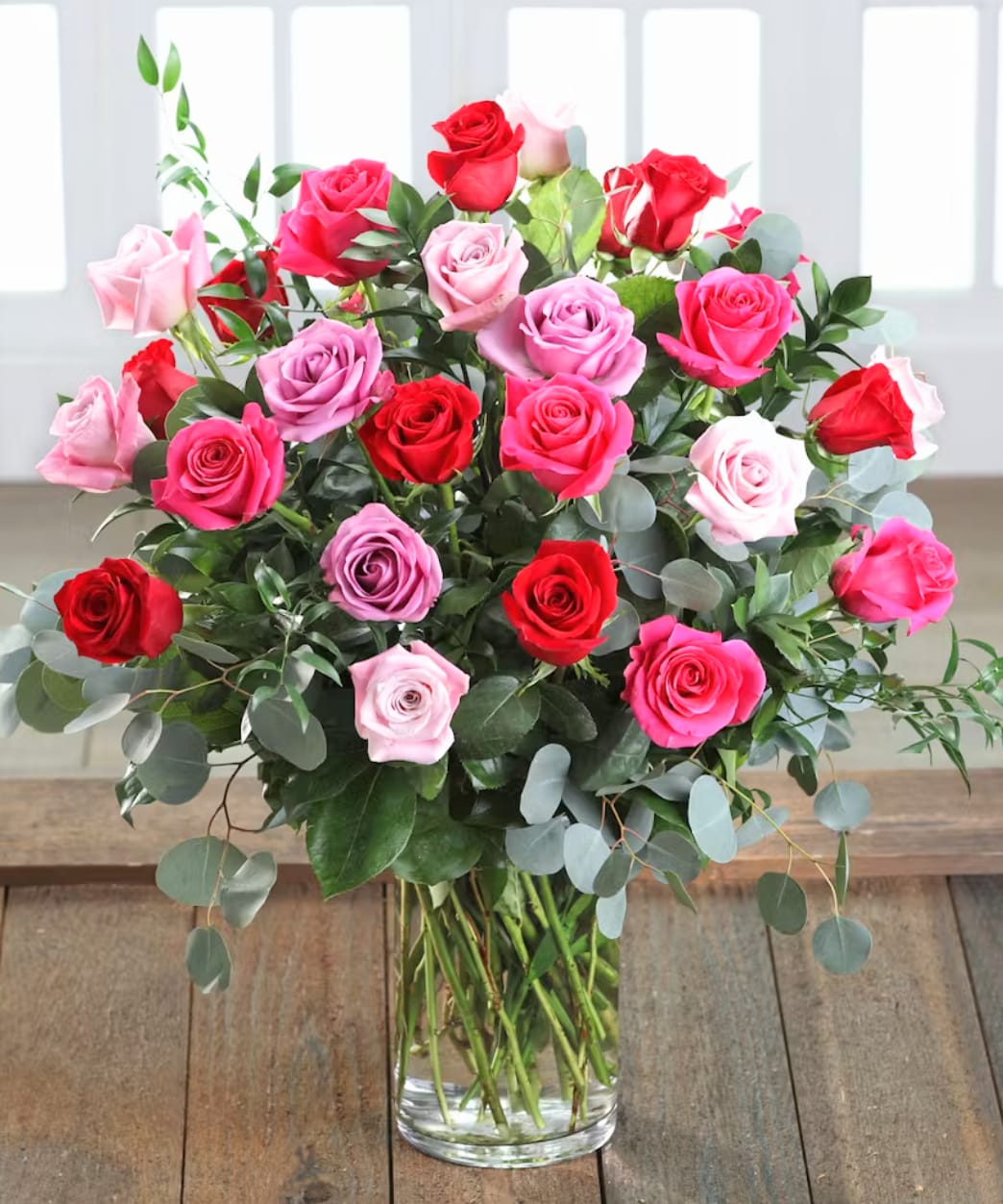 Cherished Love Cherished Love - A breathtaking stunning bouquet featuring 2 dozen roses. This beautiful arrangement is filled with red, light pink, hot pink & lavender colored roses & eucalyptus greens. Arranged tall & delivered in a clear glass vase. Measures approx. 20" tall & 20" wide