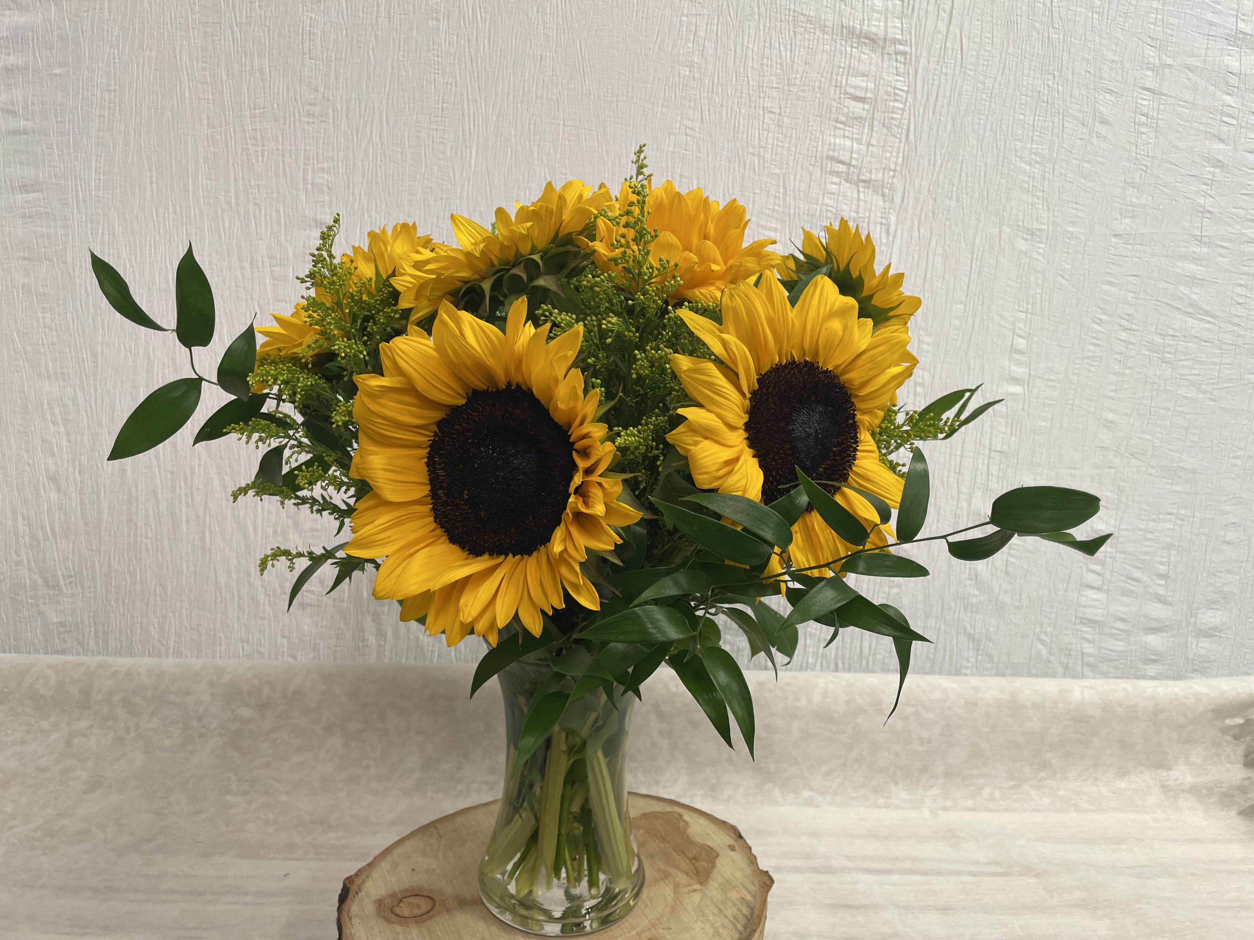 Sunny Sunflower Vase  - A beautiful cheery vase of all Sunflowers is the perfect way to brighten someone's day! Arranged in a tall glass vase with beautiful fillers and greens it is a sure way to put a smile on anyone's face! 