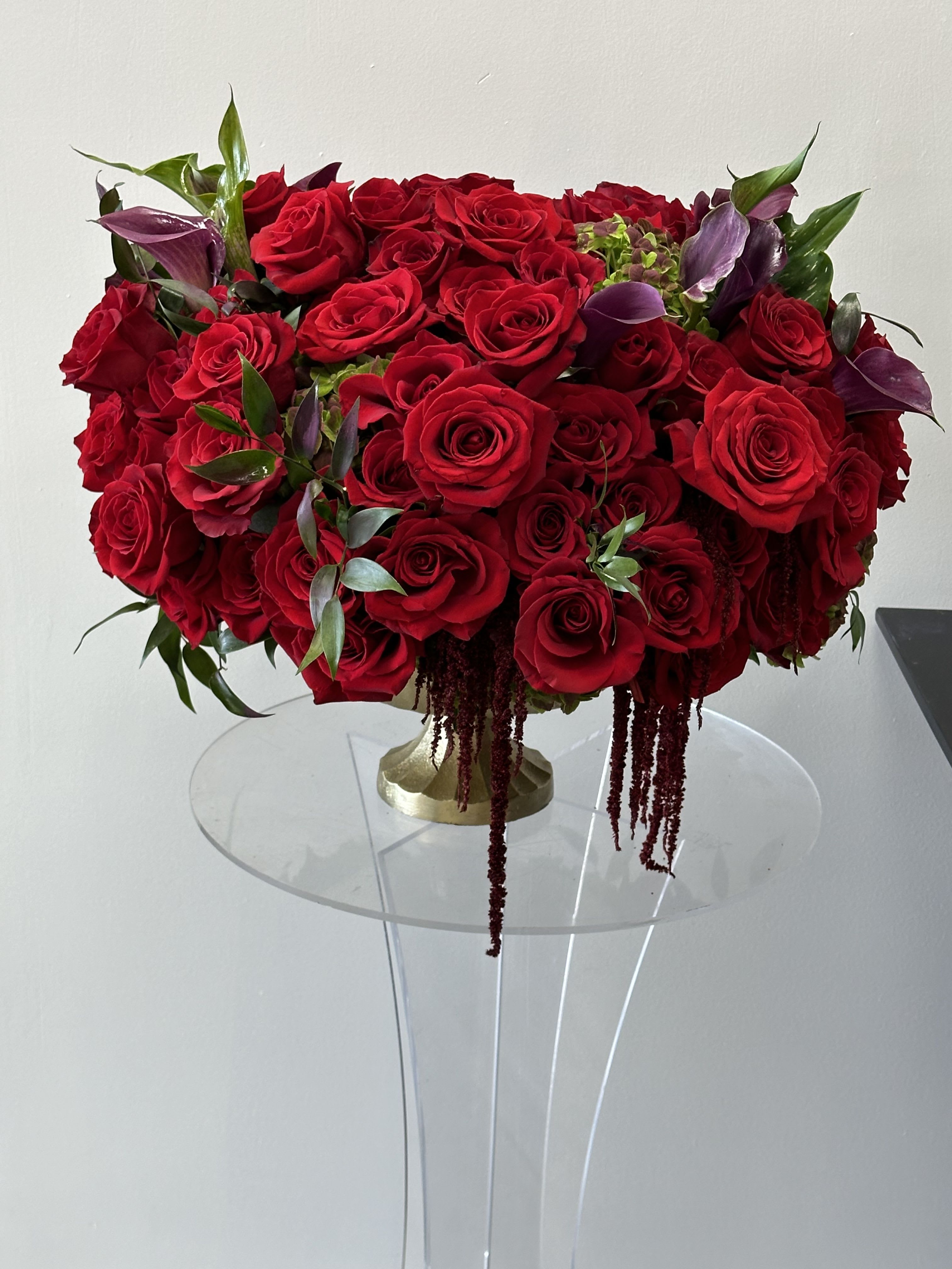 Merlot Merlot - Moody and passionate Merlot features deep red roses, deep maroon lily and burgundy Amaranthus sets the perfect mood for romance and love. Resting a stunning matt gold vase an all-time favorite for that special occasion. Some florals are seasonal, if particular flower will not be available due to season, we will substitute for similar flower, composition, color pallet and value of the arrangements as closely as possible. All effort to create a floral arrangement as close to the photo shown, the actual arrangement may vary slightly in its appearance from the photo shown. If you have any questions about your order, we welcome you to call us in or email