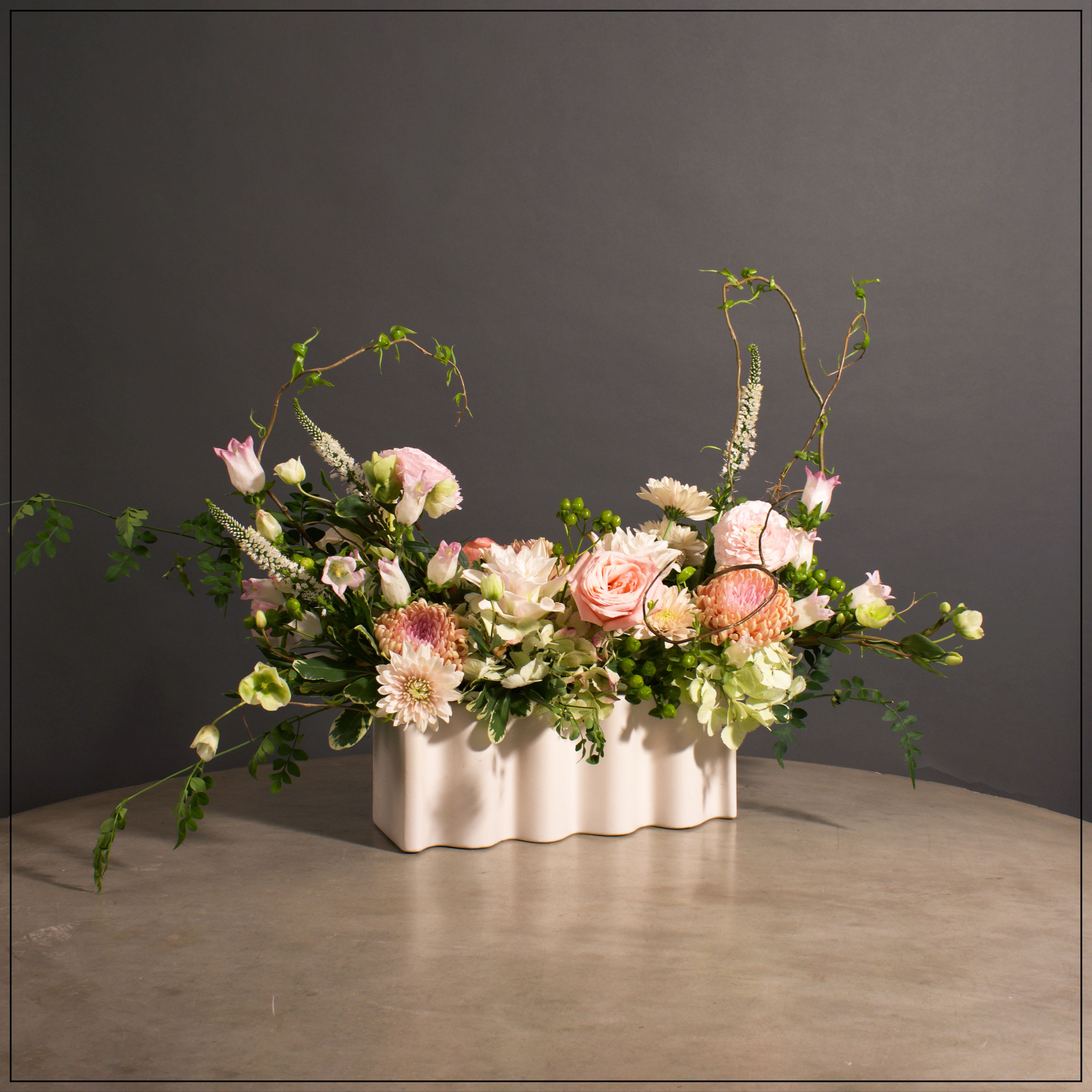 Waverly - Fabulous wave vase, filled to the brim with a beautiful assortment of hydrangea, roses, chrysanthemum, helleborus, lilies, ranunuculus, veronica, and jasmine vine. The container will be used for years.  Approximate size is 17&quot; tall and 20&quot; wide.