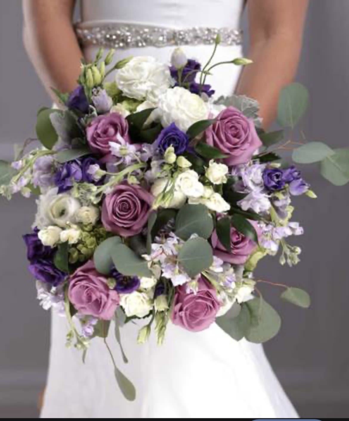Lavender and white hand held bridal bouquet Lavender and white hand held bridal bouquet - large standard lavender roses, lavender stock, white lisianthus, green hydrangea, white spray rose, eucalyptus hand tied with ribbon