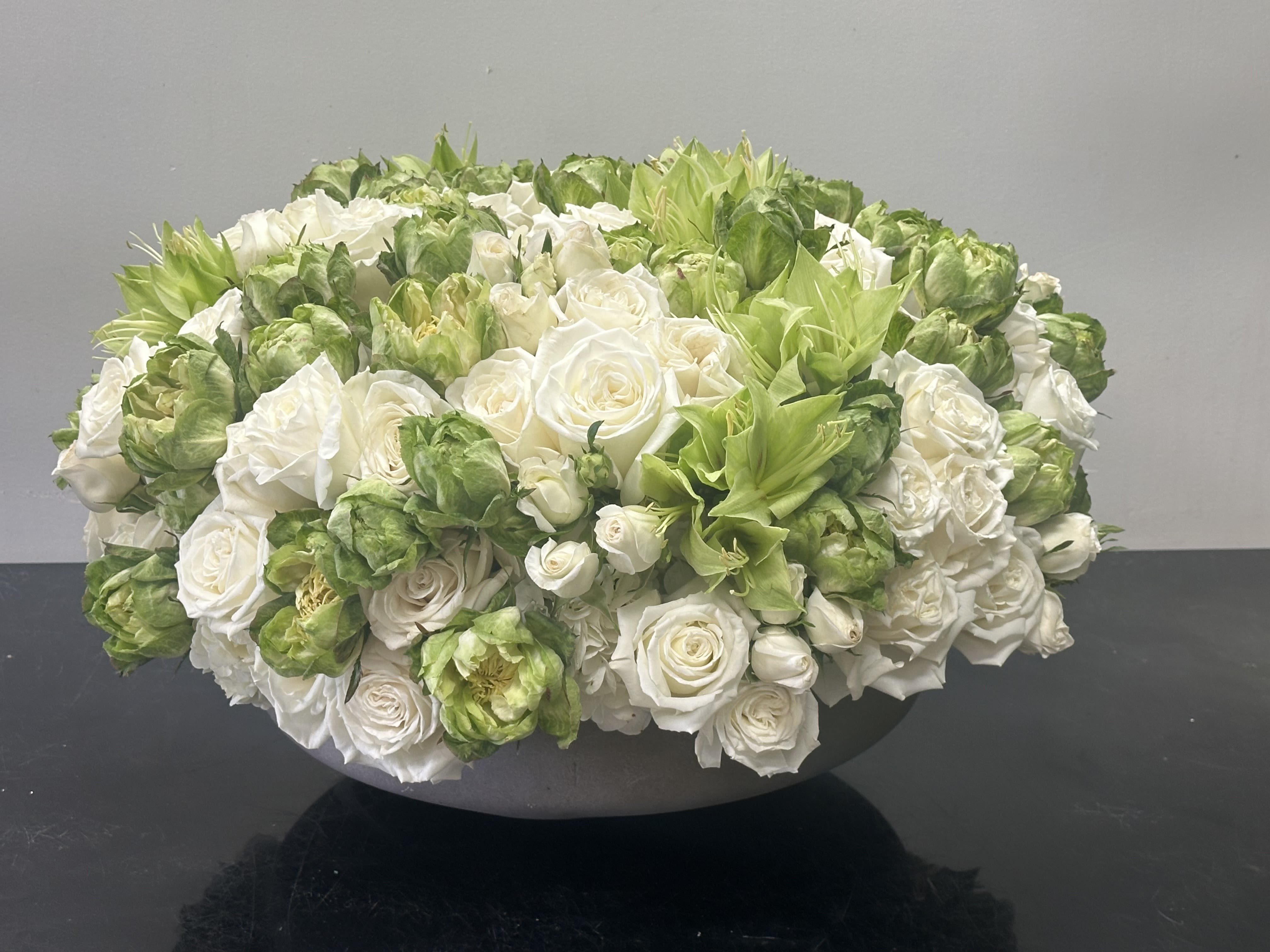 Enchanted Garden Enchanted Garden - This enchanting arrangement features a soothing tone of lime green and ivory white blooms. This composition symbolizes forever with the rose playa Blanca and sweet ruffles of the spray roses throughout. Featured with the captivating petal design of the green veggie rose with its alluring appearance and the pops of green amaryllis make this arrangement truly an enchanted garden. Resting in a beautiful ceramic gray vase. Some florals are seasonal, if particular flower will not be available due to season, we will substitute for similar flower, composition, color pallet and value of the arrangements as closely as possible. All effort to create a floral arrangement as close to the photo shown, the actual arrangement may vary slightly in its appearance from the photo shown. If you have any questions about your order, we welcome you to call us in or email