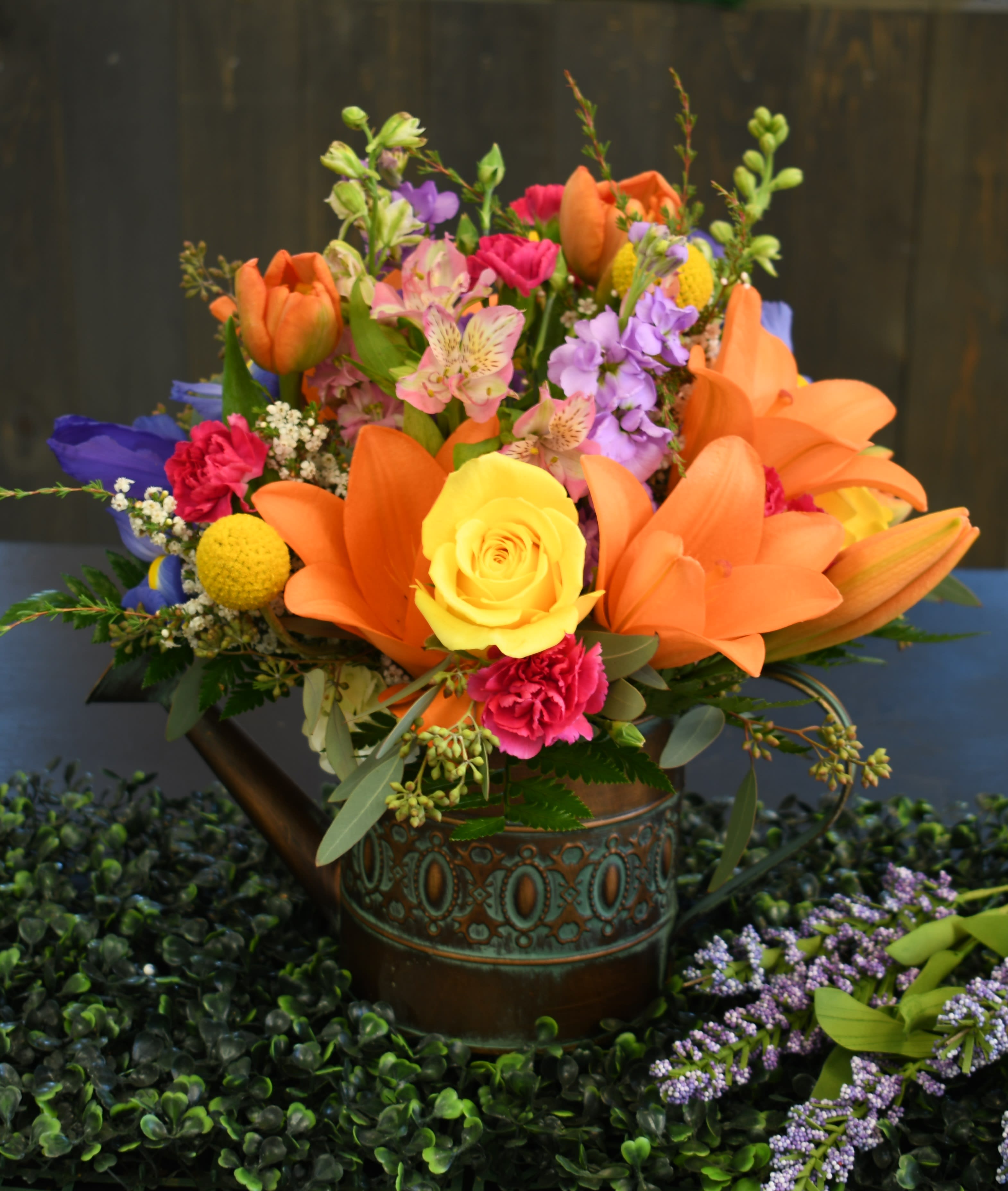 Rainbow Showers Please allow 2 days - A beautiful arrangement of brightly colored flowers in an adorable watering can. This arrangment is sure to bring a smile to your loved one's face.  Please Note: Due to the nature of flowers certain blooms pictured are seasonal &amp; not always available. We always include the best flowers available and may substitute flowers to maintain the beauty of this design. If you have any specific requests we encourage you to call and let us know before placing an order