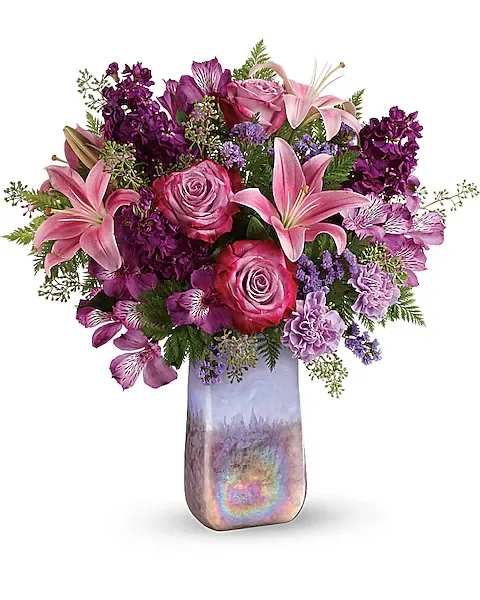 Teleflora's Amethyst Jewel Bouquet - A jewel of a gift! Bursting with a lush bouquet of lavender roses and pink lilies, this breathtaking, hand-blown art glass vase has a shimmering iridescent finish and soothing amethyst hue that's sure to make it a home décor favorite!  This bouquet features lavender roses, pink asiatic lilies, purple alstroemeria, lavender carnations, lavender sinuata statice, seeded eucalyptus, and leatherleaf fern. Delivered in an Amethyst Gemstone Art Glass vase.
