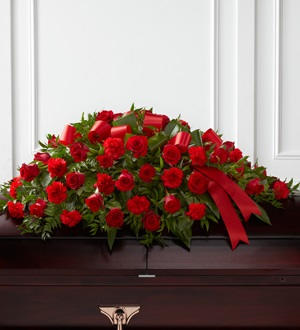 Dearly Departed Casket Spray - Rich red roses and carnations are gorgeously arranged amongst lush greens and accented with a red satin ribbon to create the ideal adornment for their casket at their final farewell service.