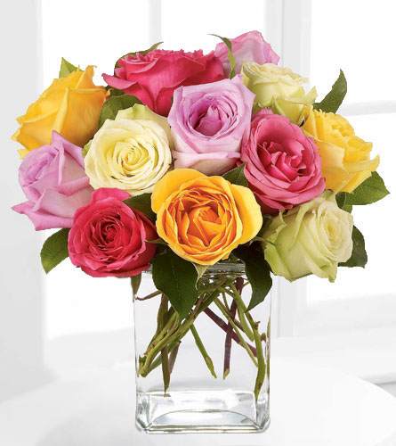 Rose Fest Arrangement - Send a beautiful premium rose arrangement in the colors of the rainbow. A dozen mixed colored roses arrive with greenery, designed in a rectangular glass vase. This fresh and festive arrangement is perfect for an anniversary, birthday or important occasion. Rose color combinations will vary depending on availability.