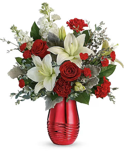 Teleflora's Radiantly Rouge Bouquet - Sweep them off their feet with this luxurious bouquet of red roses and fragrant white lilies, presented to perfection in a radiant rouge ceramic vase!  Red roses, white asiatic lilies, red carnations, red miniature carnations, and white stock are arranged with dusty miller, parvifolia eucalyptus, and lemon leaf. Delivered in a Radiantly Rouge V