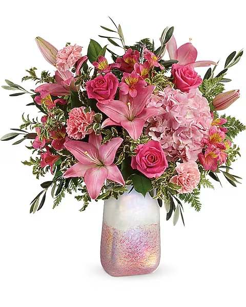 Teleflora's Blushing Gemstone Bouquet - Inspired by rose quartz, the gemstone symbolizing love, this iridescent art glass vase and luxurious pink rose bouquet blushes with romance!  This feminine bouquet features light pink hydrangea, hot pink roses, pink asiatic lilies, pink alstroemeria, light pink carnations, olive branches, leatherleaf fern, pitta negra, and lemon leaf. Delivered in a Pretty in Quartz vase.