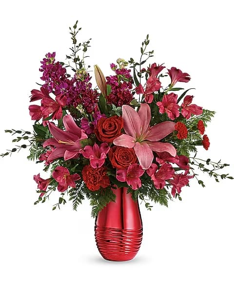 Teleflora's Beyond Radiant Bouquet - Beyond memorable! Make a big, bold and beautiful Valentine's Day statement with this romantic red bouquet in a radiant metallized ceramic vase!  Red roses, pink asiatic lilies, dark pink alstroemeria, red carnations, red miniature carnations, and fuchsia stock are arranged with parvifolia eucalyptus, leatherleaf fern, and lemon leaf. Delivered in a Radiantly Rouge vase.