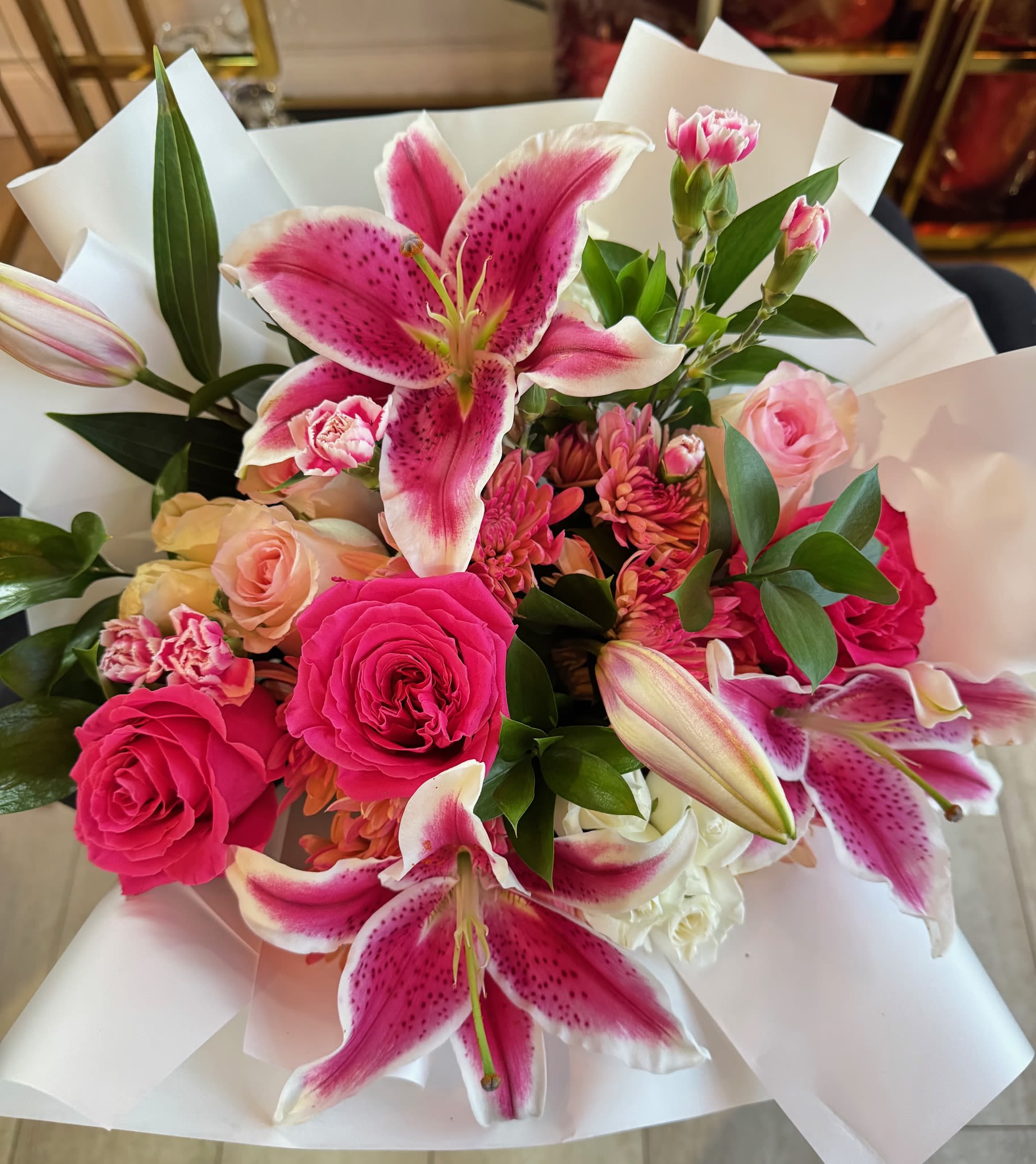 Fleur Modern Bouquet - Radiant and full of life, this striking bouquet is a bold expression of love and admiration. Featuring vibrant stargazer lilies, deep fuchsia roses, soft blush spray roses, and charming pink carnations, it’s a stunning blend of passion and tenderness. The crisp white wrap creates a modern, elegant contrast, making this arrangement perfect for the mother who deserves to feel celebrated and adored. Bright, joyful, and full of heart—just like Mom.