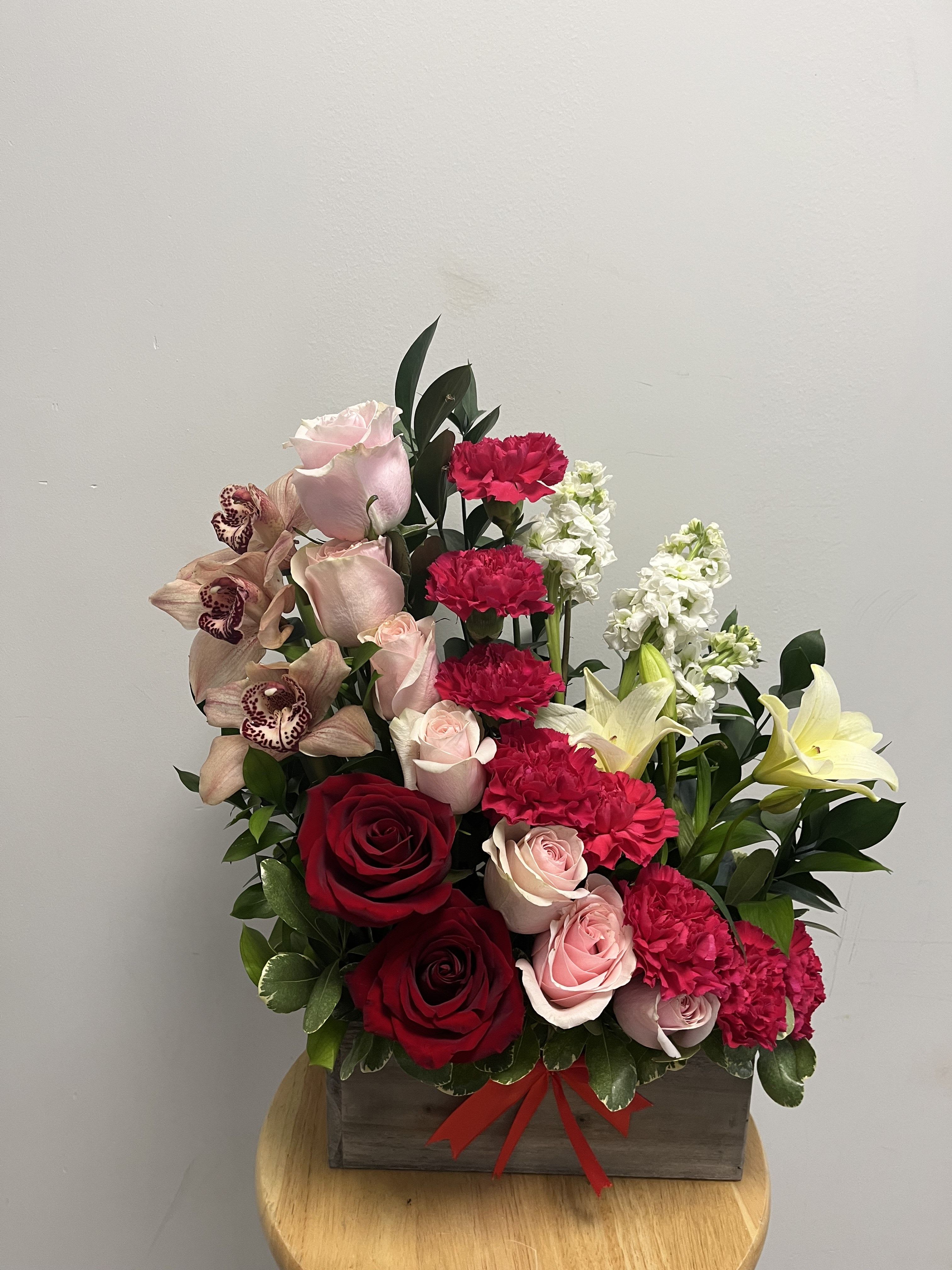 Stairway to Heaven Stairway to Heaven - This beautiful arrangement features red roses, cymbidium orchids, pink roses, hot pink carnations, white lilies, white stock and ruscus in a beautiful spiral design. Presented in a rustic wooden box, this arrangement is perfect for birthdays and anniversaries.