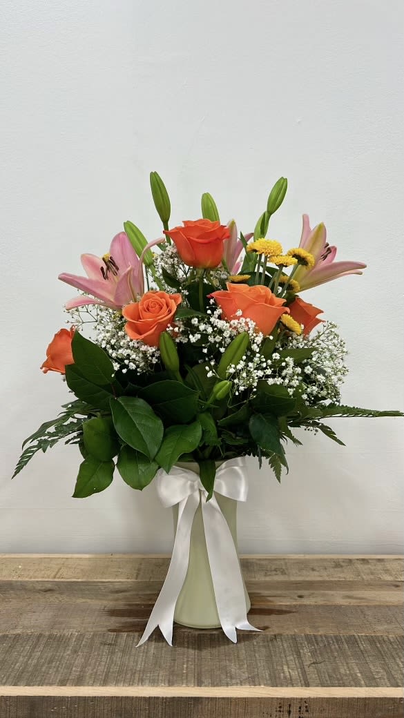 Sunset Dream - With striking pink lilies and bright orange roses, softened by delicate baby’s breath. Housed in a tall, colorful vase, this bouquet brings the warmth and wonder of a perfect sunset into any space, creating an unforgettable impression.
