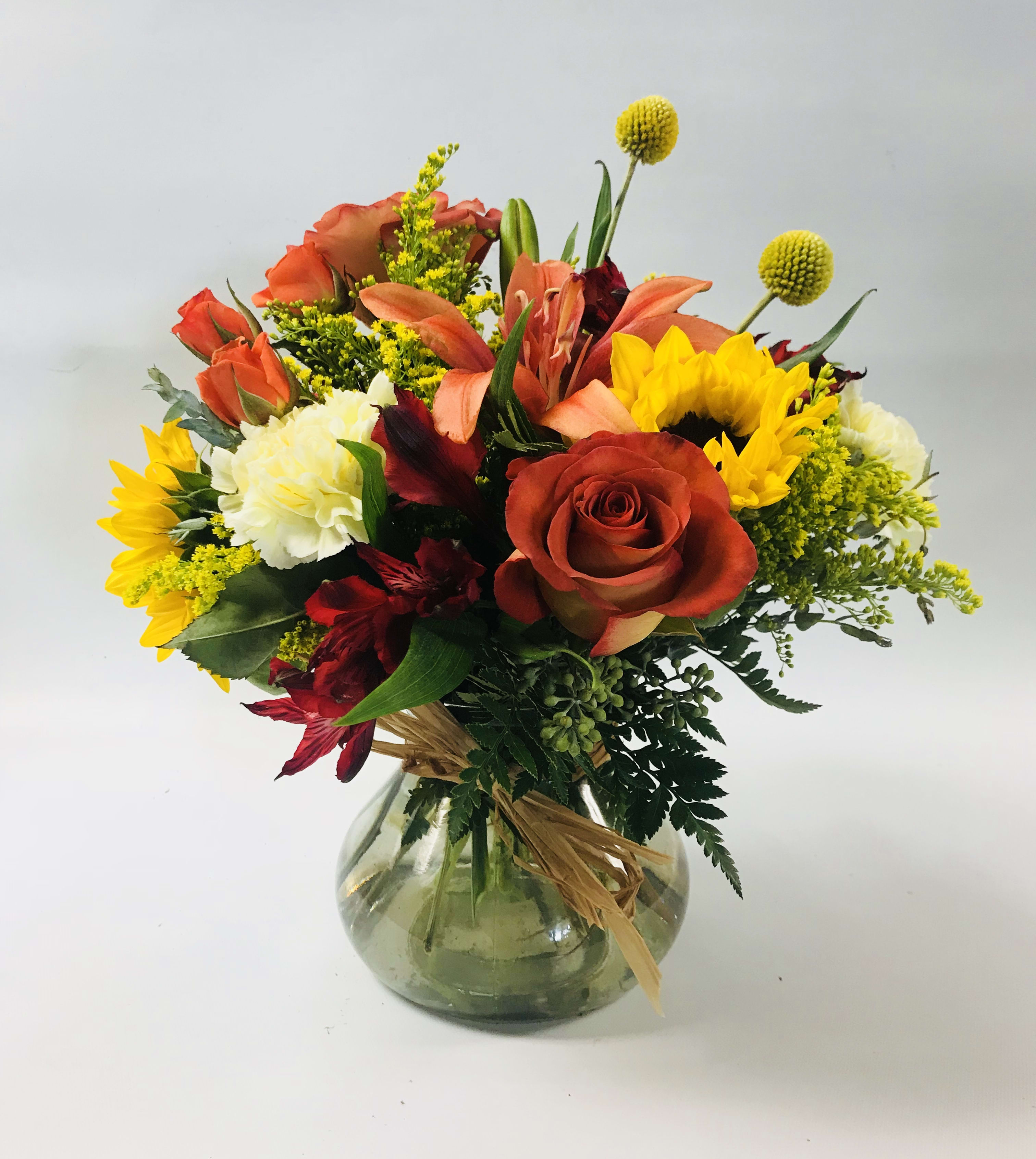 Autumn Awakening  - A homey selection of oranges, rusts, and yellows are perfect for any Autumn day. Includes  orange roses and lilies, sun flowers, orange spray roses, yellow carnations, etc. Standing apprx. 13&quot; tall.