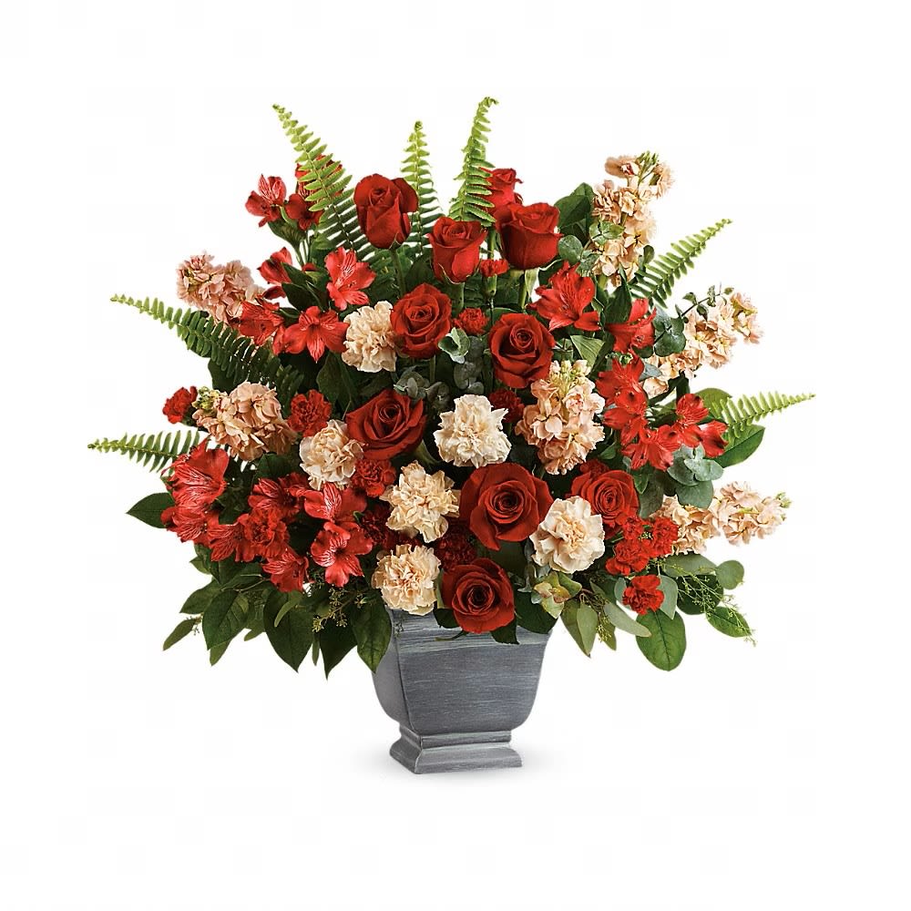 BOLD TRIBUTE BOUQUET - A bold expression of your deepest condolences, this elegant mix of red and peach blooms in a large antiqued pot brings strength and comfort. Red roses, red alstroemeria, peach carnations, miniature red carnations, and peach stock are arranged with spiral eucalyptus, seeded eucalyptus, sword fern, and lemon leaf. Delivered in a Modern Heritage pot.