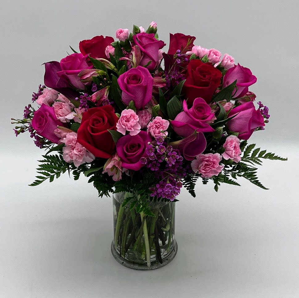 Precious Precious - The power of pink is packed into one beautifully blushing bouquet to make your recipient's day one they will never forget! hot pink and red roses with light pink mini carnations arranged in a crystal cylinder vase accented with lush greens Berried bliss in every way, this bouquet is set to create a standout birthday, congratulations, or thank you gift.