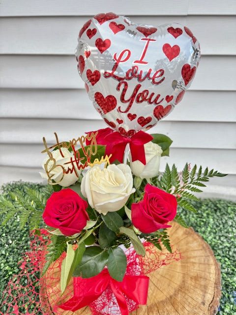 Always you  - ​​“Roses for love. Balloons for joy. You for always.”  This arrangement is like a love song wrapped in birthday sparkle. Picture a clear glass vase—tall, classic, and gracefully curved—cradling a lush bouquet of red and white roses. The red roses pulse with romantic intensity, while the white ones offer a soft, graceful balance, symbolizing pure devotion and sincerity.  The stems are carefully hand-tied and finished with a rich red satin ribbon, its bow cascading down the vase like a flourish of passion. Rising above the bouquet is a floating “I Love You” balloon, heart-shaped or classic round, shimmering with affection and playful charm.  Nestled into the arrangement or clipped elegantly to the vase is a “Happy Birthday” emblem—perhaps a gold-accented tag or a cheerful acrylic pick that gleams like a party whisper. Together, it’s a heartfelt fusion of romantic and celebratory vibes, perfect for telling someone they’re loved and celebrated, all at once.