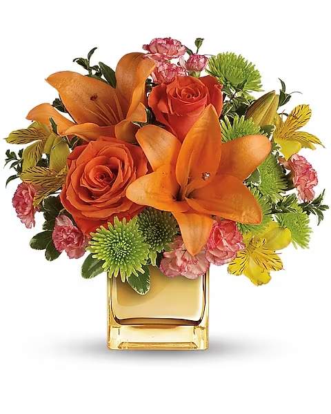 Teleflora's Tropical Punch Bouquet - Glow for it! Capture the magic of a tropical sunset with this gorgeously glowing bouquet. Lush lilies and roses in radiant shades of orange and yellow are presented in a golden Mirrored Cube for a touch of instant glam.  Soft orange roses, asiatic lilies and miniature carnations are arranged with yellow alstroemeria and green button spray chrysanthemums. Delicate oregonia and pittosporum add contrast. Delivered in a Mirrored Cube.