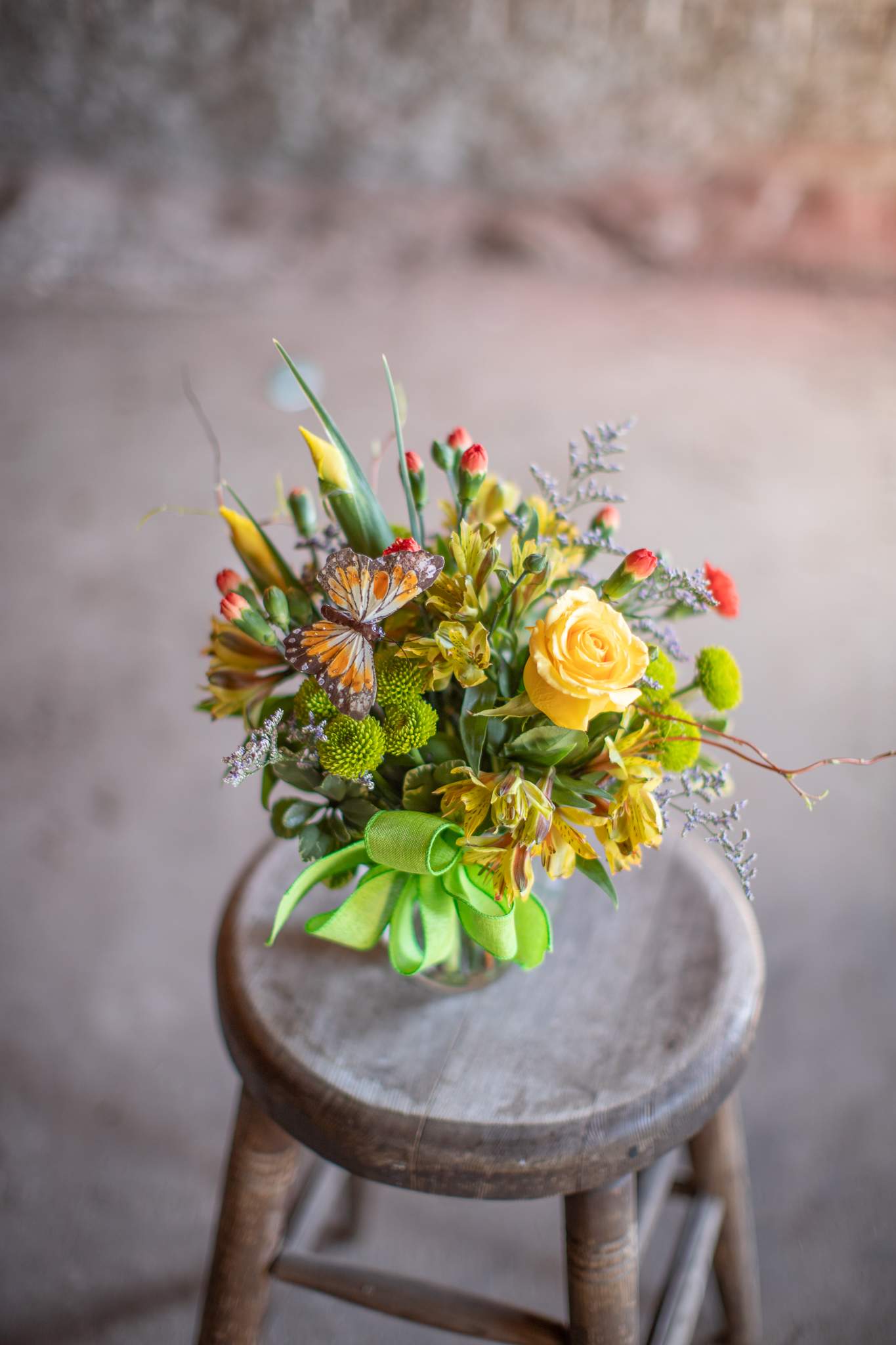 Bubbly Butterfly - This perky little arrangement is the perfect pick me up! A floral design inspired by garden whimsy and outdoor charm. Colorful flowers are arranged in a cute fluted bubble bowl style vase. The design is complete with an adorable butterfly in colors that compliment the floral selections and accompanying handcrafted bow. Colors and assortments may vary from the photo.