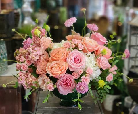Ava Ava - Ava by Windmill Floral Expressions in Las Vegas is a romantic floral daydream—an airy, pastel-toned composition that evokes the softness of a watercolor painting come to life. Designed with delicate precision and artistic flair, Ava is a celebration of elegance, femininity, and gentle beauty. Blush pink and apricot peach roses bloom in full, velvety layers, surrounded by ruffled stock, spray roses, and cloudlike white hydrangeas that create a luminous, voluminous base. Sprigs of chartreuse bupleurum and airy scabiosa add mrovement and whimsy, arching softly to create a natural, garden-like flow. Housed in a low-profile dark green vessel, the contrast enhances the ethereal color palette, allowing the florals to shine in serene harmony. Perfect for weddings, anniversaries, sympathy arrangements, or as a refined centerpiece, Ava brings a sense of calm, beauty, and quiet luxury to any space. Available for delivery in Las Vegas and Henderson.