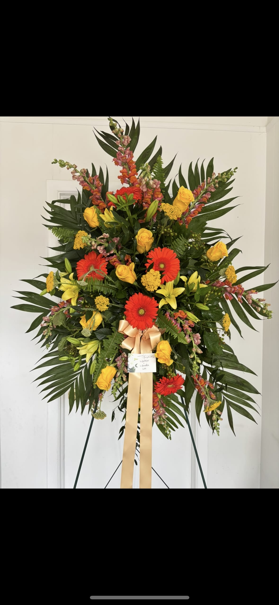 Standing Spray Yellow and Orange  - Standing spray with orange gerbera daisy, yellow roses, orange snap dragon, yellow Lillies, yellow filler flower. Finished with premium greens. 