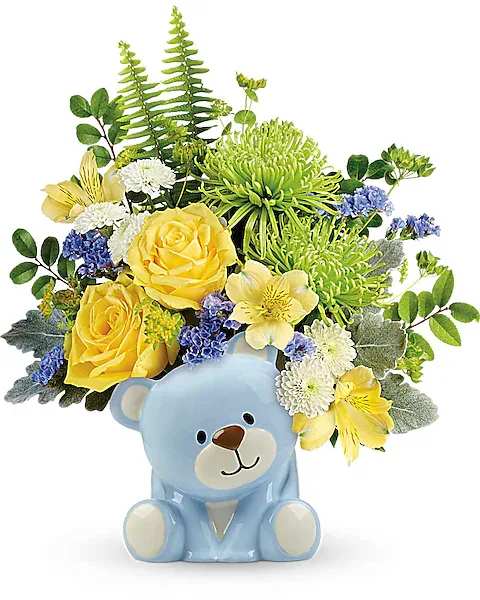 Teleflora's Joyful Blue Bear Bouquet - Welcome the new bundle of love with this sunny yellow rose bouquet, charmingly presented in a sweet ceramic teddy bear.  This joyful arrangement features yellow roses, yellow alstroemeria, green spider chrysanthemums, white button spray chrysanthemums, blue sinuata statice, bupleurum, dusty miller, huckleberry, and sword fern. Delivered in a baby blue Bundle of Love Bear.