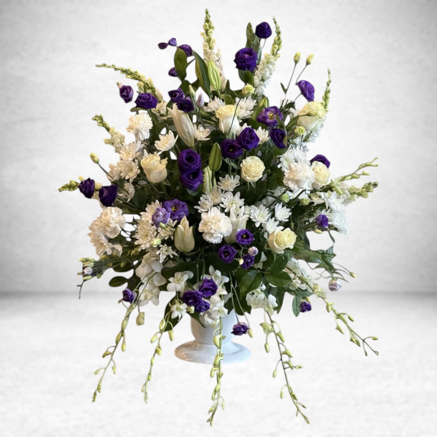 Moonlit Majesty - A stunning symphony of elegance, &quot;Moonlit Majesty&quot;  captures the essence of grace and sophistication. Pristine white roses symbolize purity and admiration, while delicate orchids add an exotic touch of luxury. Towering snapdragons bring height and drama, creating a dynamic contrast. Soft purple fillers weave through the arrangement, adding depth and a regal charm. This breathtaking combination radiates serenity and refinement, perfect for celebrations, heartfelt expressions, or a timeless display of beauty.
