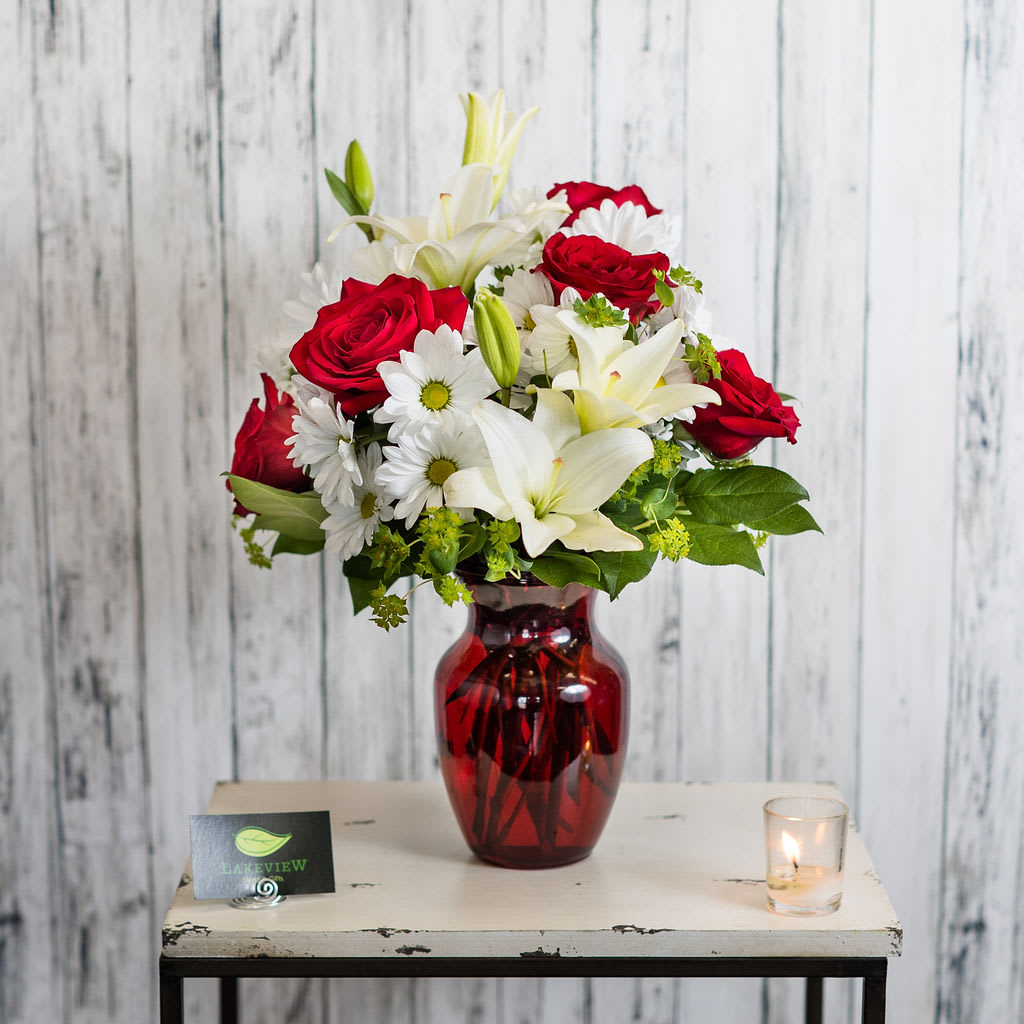 Romance - A classic favorite!  White lilies, red roses and daisies in a red glass vase- what more could you ask for?  Approximate Dimensions: 14&quot; H x 18&quot; T