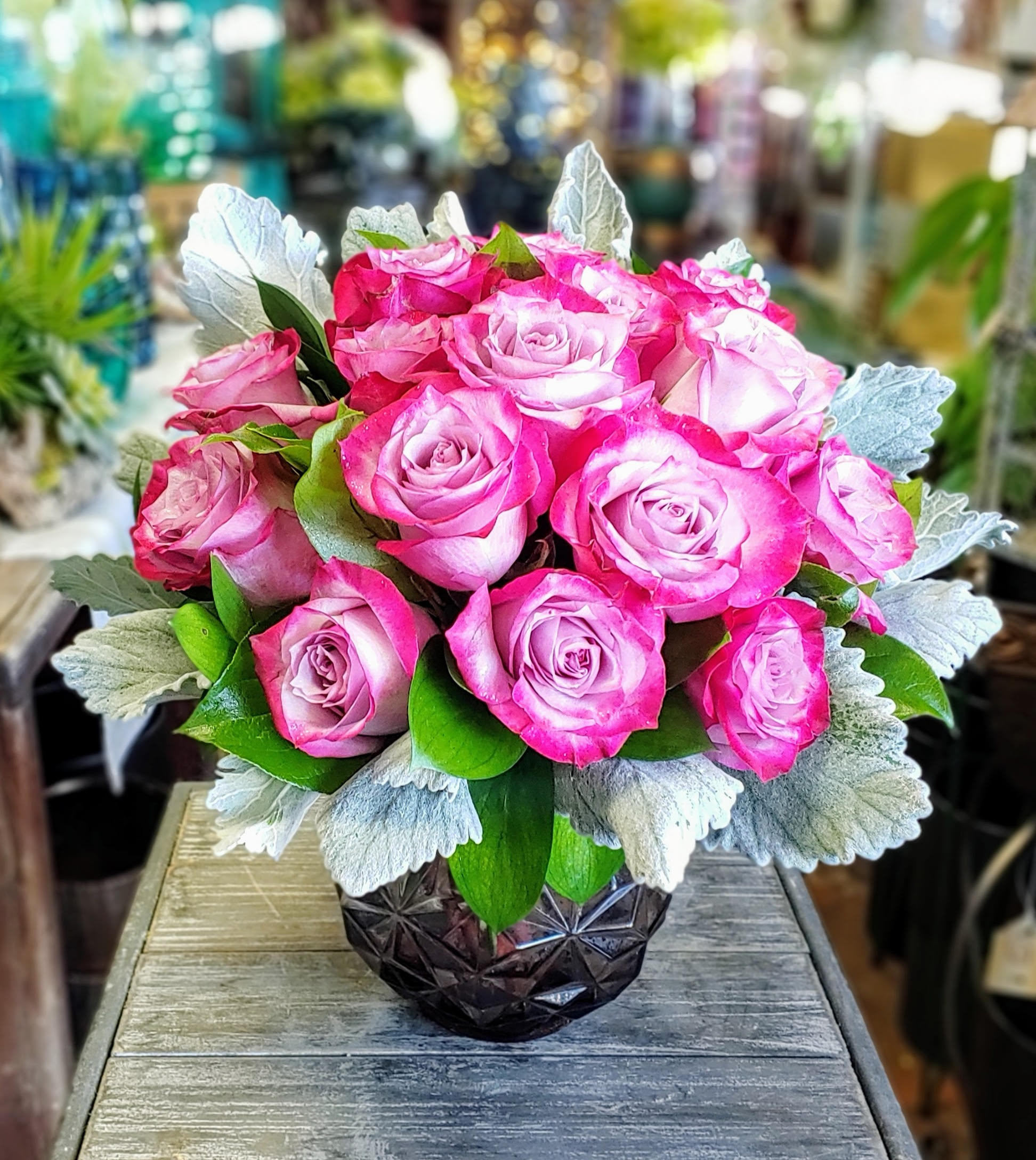 Stella - Stella – A Brilliant Burst of Elegance Bright, bold, and endlessly charming, Stella is a luxury floral arrangement that lights up any room like a star. Bursting with 20 vivid lavender and fuchsia roses arranged in a compact, modern design, this bouquet radiates joy and confidence. Silvery dusty miller leaves and glossy greenery frame the blooms with softness and contrast, while a faceted smoky glass vase adds a touch of modern glamour and refinement.  Perfect for birthdays, anniversaries, celebrations, or simply to make someone feel luminous, Stella is a vibrant expression of affection and admiration. Its striking color and sculpted silhouette make it a standout choice for both contemporary and classic spaces.  Available for same-day flower delivery in Las Vegas and Henderson from Windmill Floral Expressions, your trusted source for high-end floral design,  rose arrangements, and unique boutique blooms.