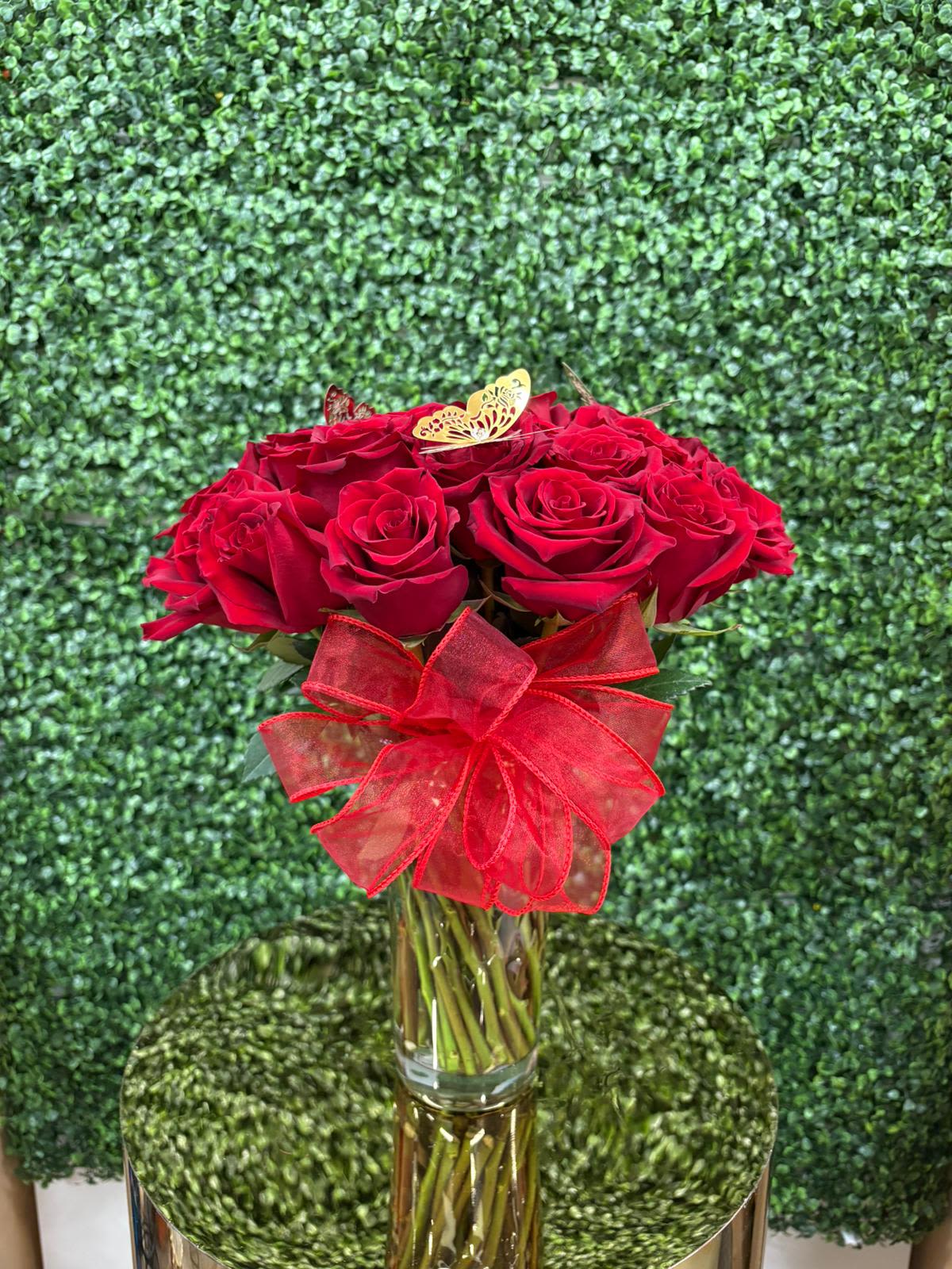 25 Roses in the wind with a glass vase. - An arrangement that speaks for itself... Twenty-five red roses that whisper love, passion and elegance, like a soft wind that caresses the soul. Presented in a thin glass vase, this bouquet is the perfect gift to express intense and eternal feelings.