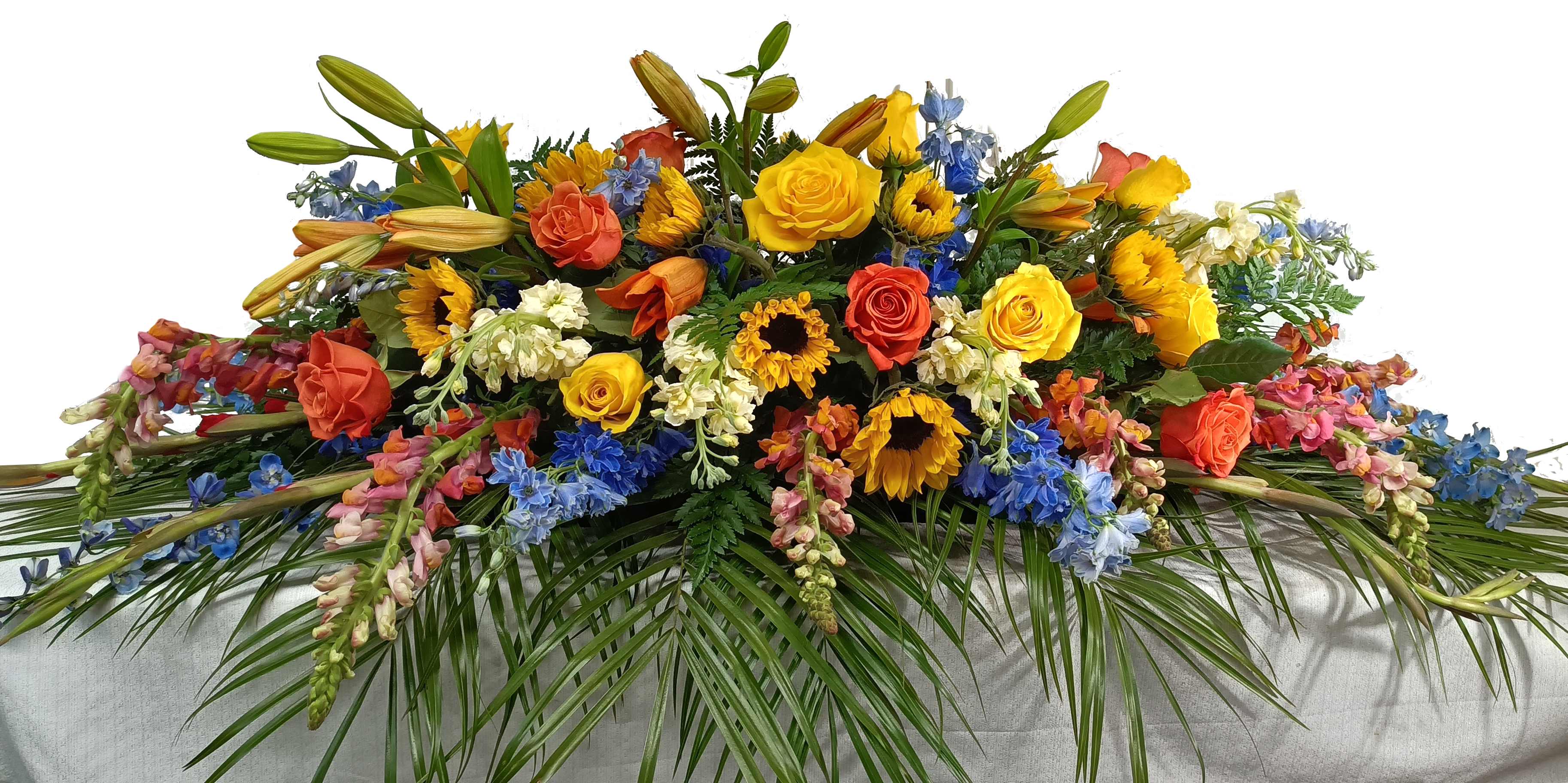 Forever in our heart Forever in our heart - This beautiful casket piece includes sunflowers , yellow roses, blue delphinium, sunflowers, orange lilies, and snapdragons with greens.