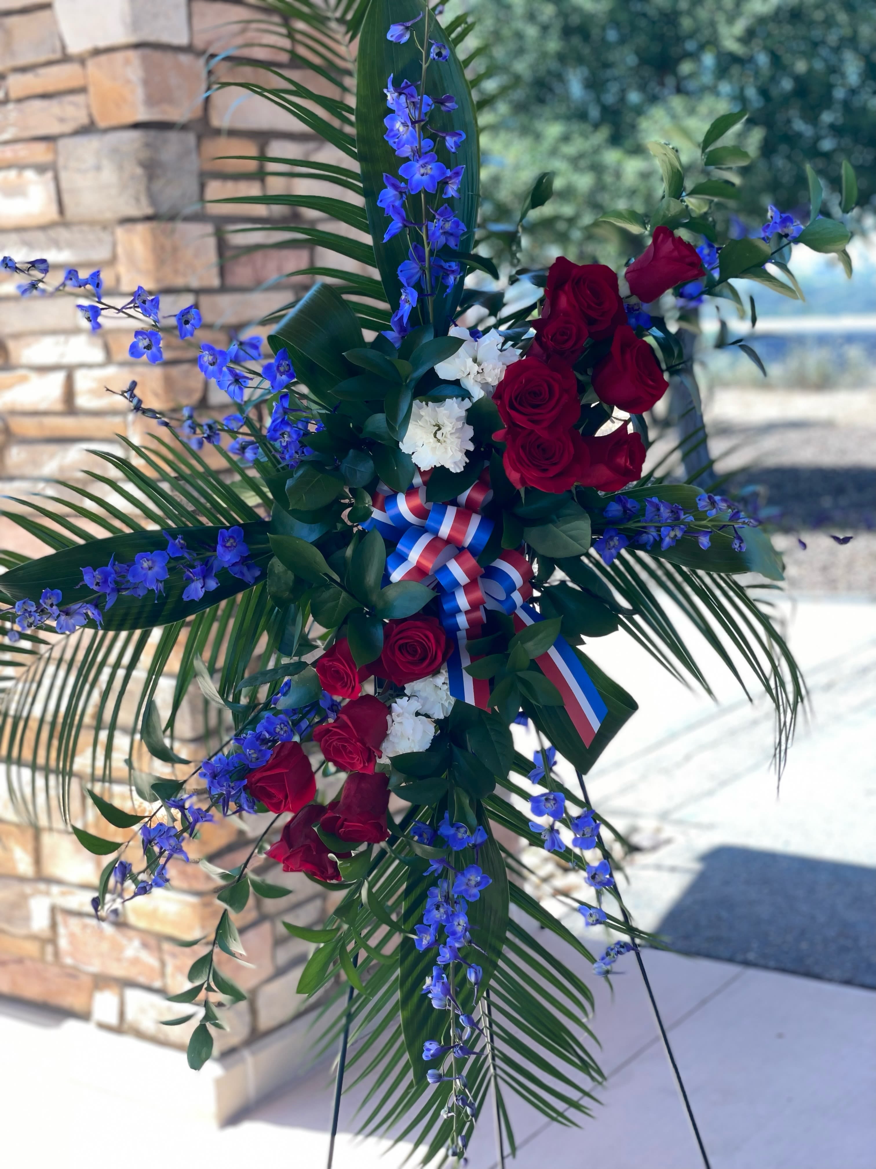 Patriotic Pride Tribute Patriotic Pride Tribute - Honor an celebrate a life of service with our patriotic Funeral Spray. Featuring vibrant red, white and blue flowers, this stunning arrangement symbolizes pride, respect and gratitude. Perfect for paying tribute to a loved one who served their country, this elegant spray offers a heartfelt farewell filled with patriotic spirit and dignity.