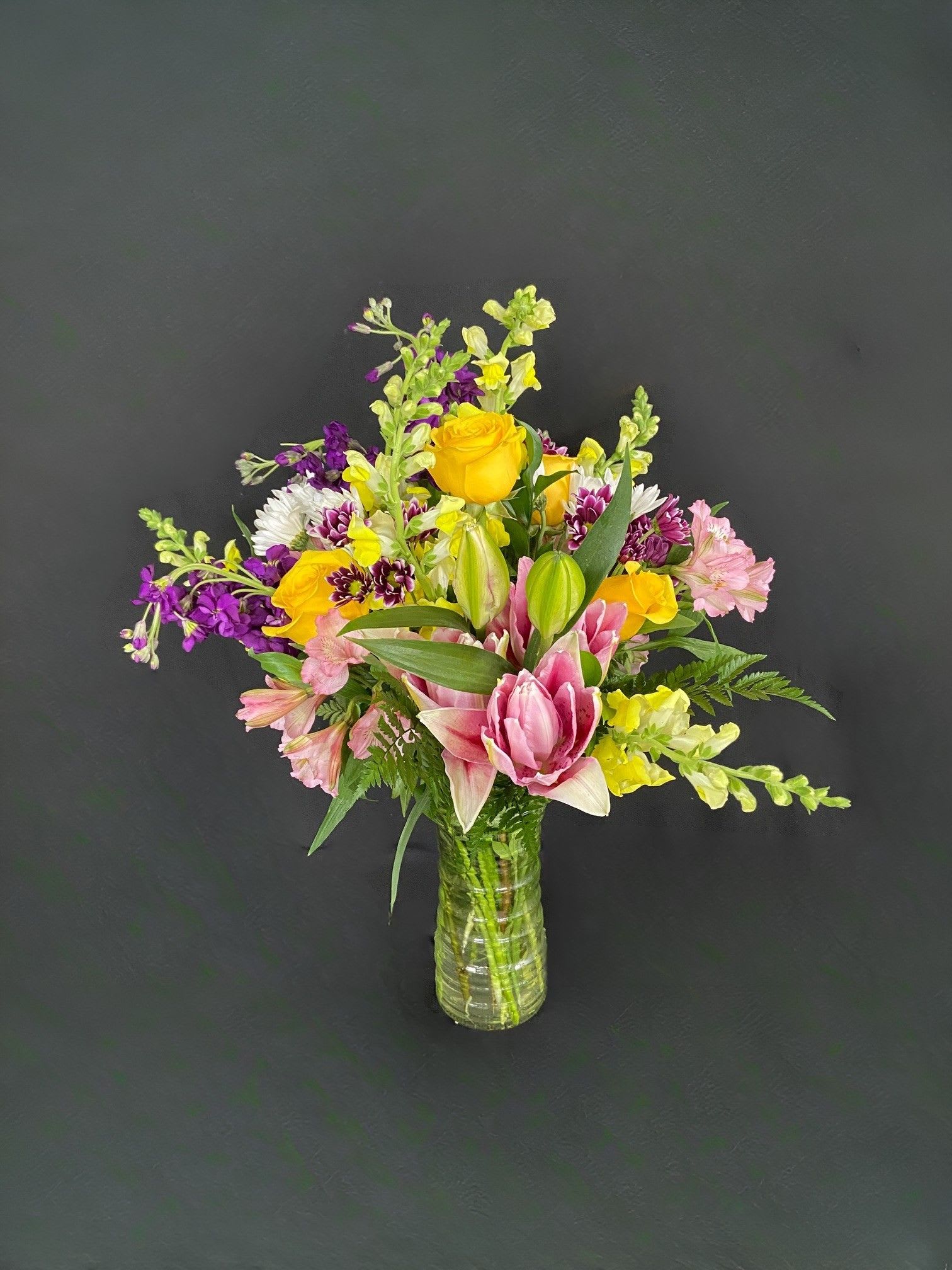 Delightful Jewels - Straight from the creative minds of our design team, this Delightful Jewels arrangement was originally made as a designer's choice; however, the customer who received it loved it SO MUCH that she ordered it for someone else less than a week later. With feedback like that, we had to name it and add it to the website! Delightful Jewel's includes yellow snapdragons, magenta stock, pink alstroemeria, white &amp; purple daisies, yellow roses, and pink oriental lilies (or rose lilies depending on availability). 