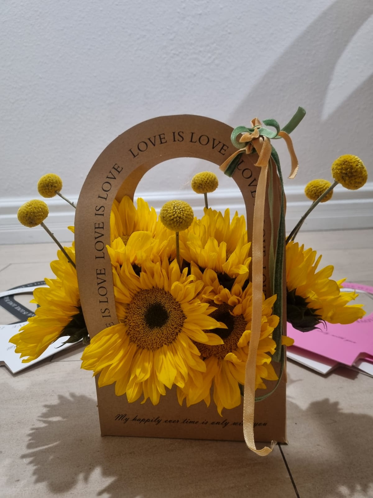 Sunshine Bloom Tote - Nestled in charming kraft tote that reads love is love, this floral gift box exudes warmth, positivity, and a touch of rustic elegance. you can order in different color of box and also you can choose this design with any flowers you like inside the box and in your preferred color.