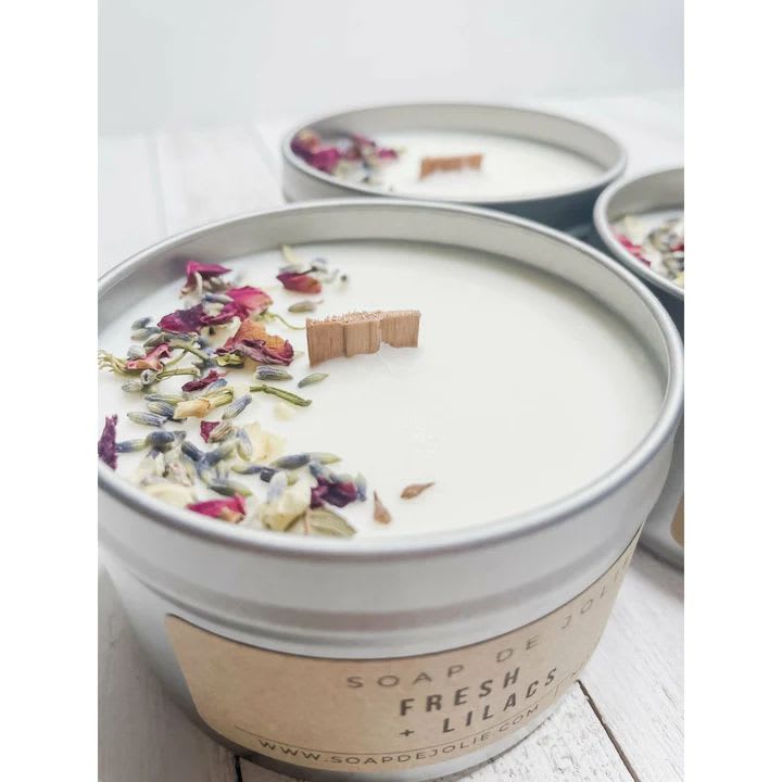 Fresh Lilacs Candle Tin - Hand poured 8 oz tin candles filled with 6 oz. of soy wax, fitted with a wooden wick. Soy wax is a more pure, longer burning wax, giving each candle a longer burn time while enjoying the soft crackling sound from the wooden wick. Notes of green leaves, lily of the valley, and honeysuckle blossoms enhance the alluring bouquet of French lilacs. Clean powder and woody amyris round out this floral scent.