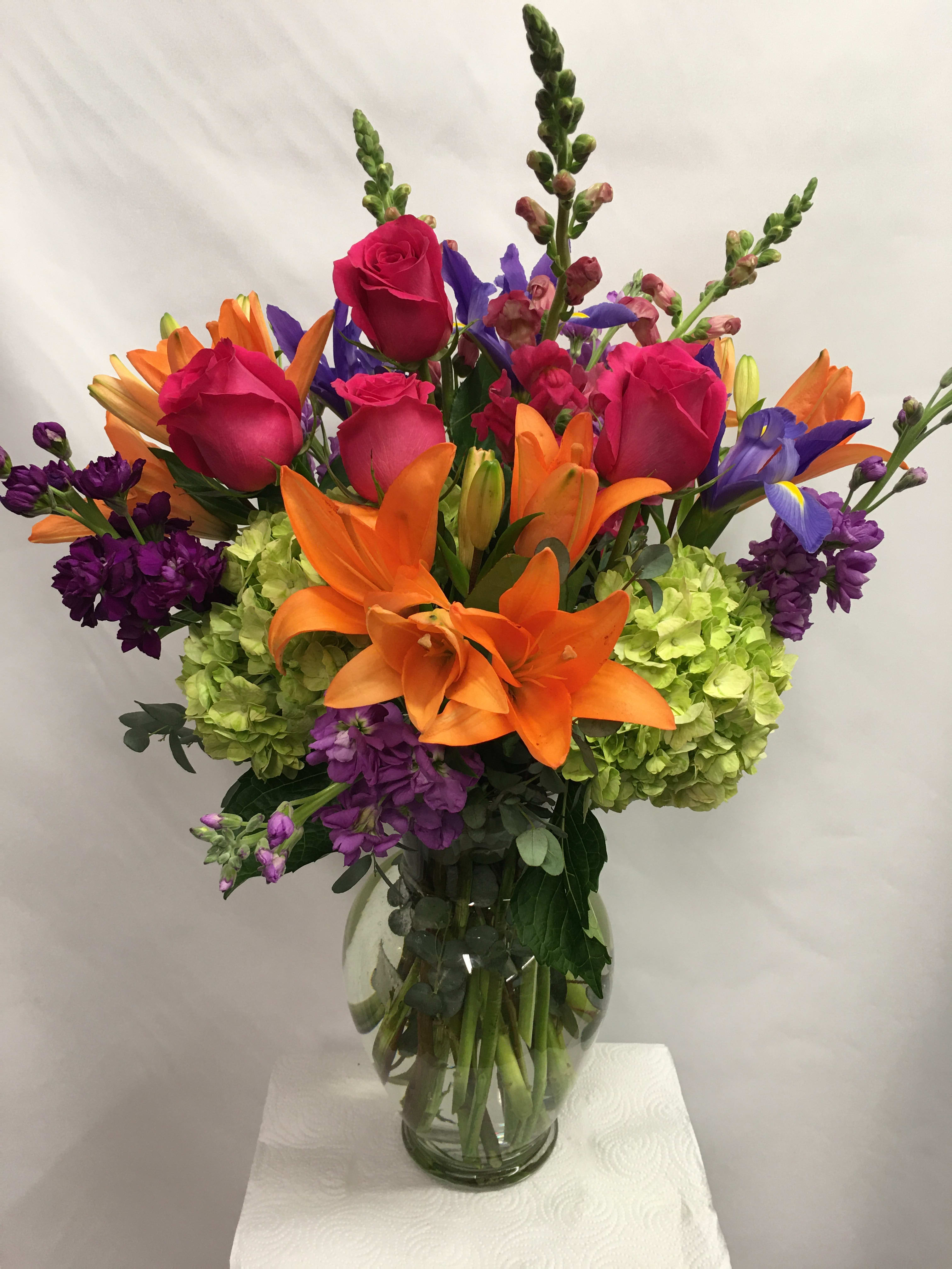 Summer Sunrise  - Bright and vibrant colors are the key to this happy flower arrangement. The vibrant lilies, roses, hydrangea, iris and other seasonal flowers compliment each other and are sure to put a smile on a special persons face! 